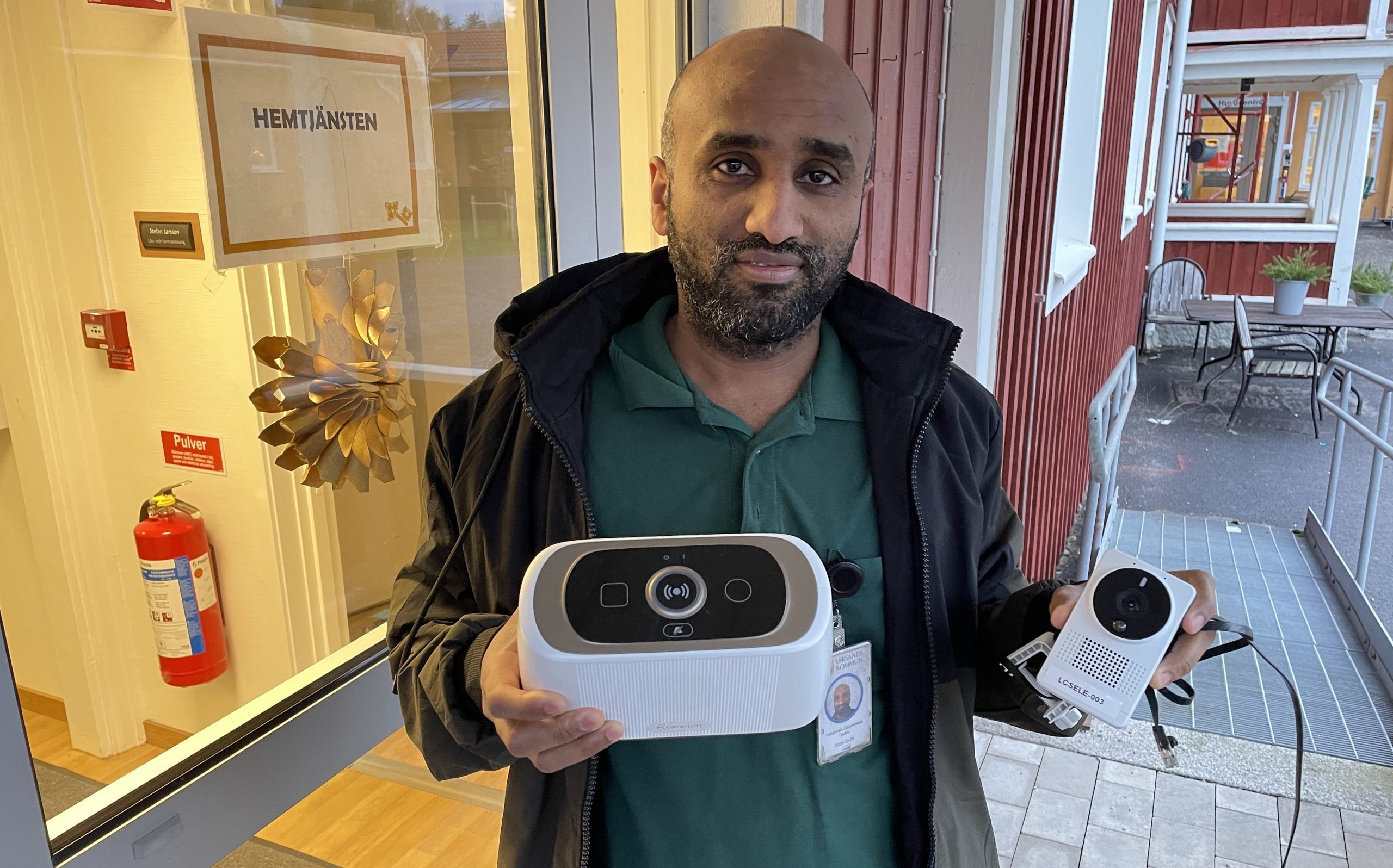 Yohannes Gebrehiwet på Leksands hemtjänst håller fram en huvudenhet till trygghetslarmen och en kamera som de boende kan bevakas genom.
