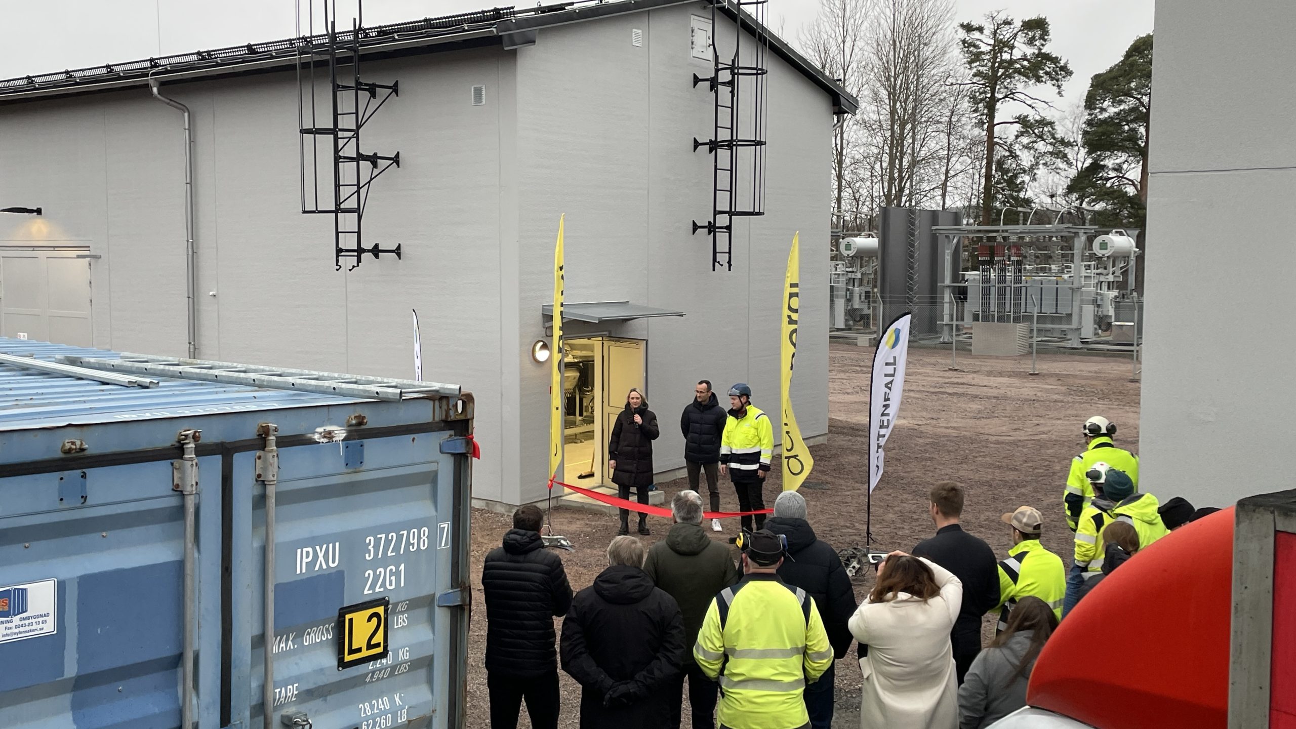 En grupp anställda har samlats framför invigningsbandet och den nya byggnaden.