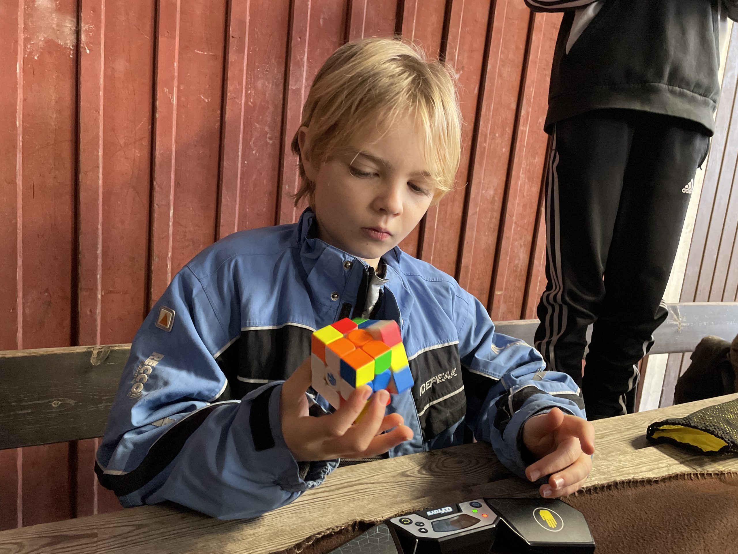 Pojke i blå jacka vrider på kuben med en hand