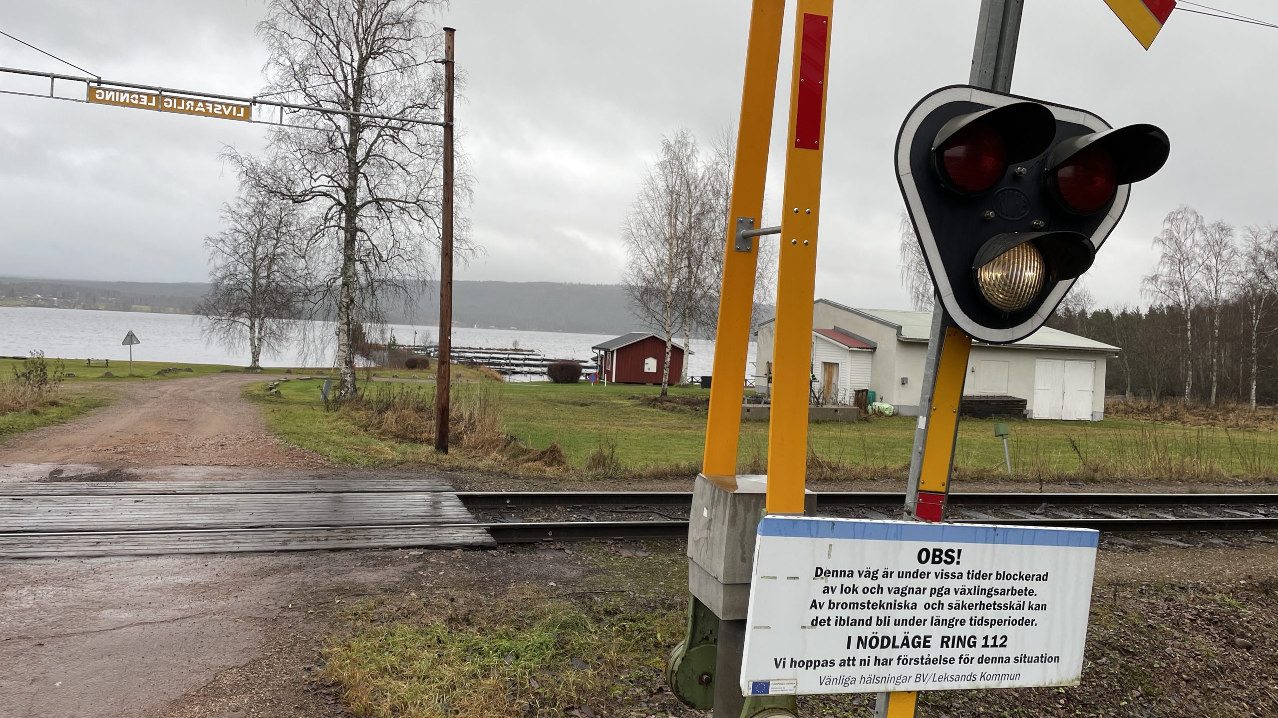 Skylt vid järnvägsövergång som varnar för att korsningen kan blockeras av stillastående tåg.