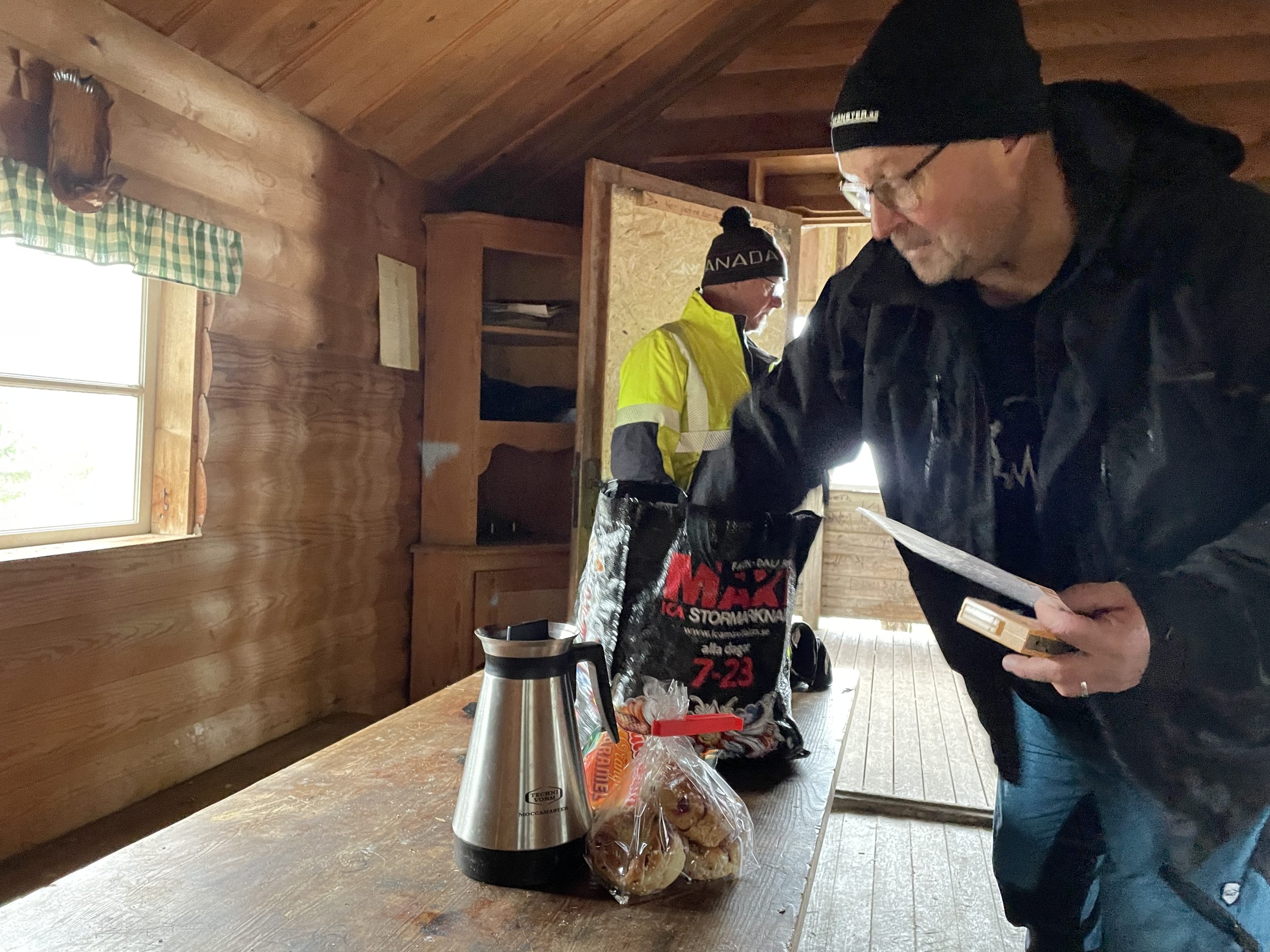 En man plockar upp kaffe och bullar ur en medhavd påse.