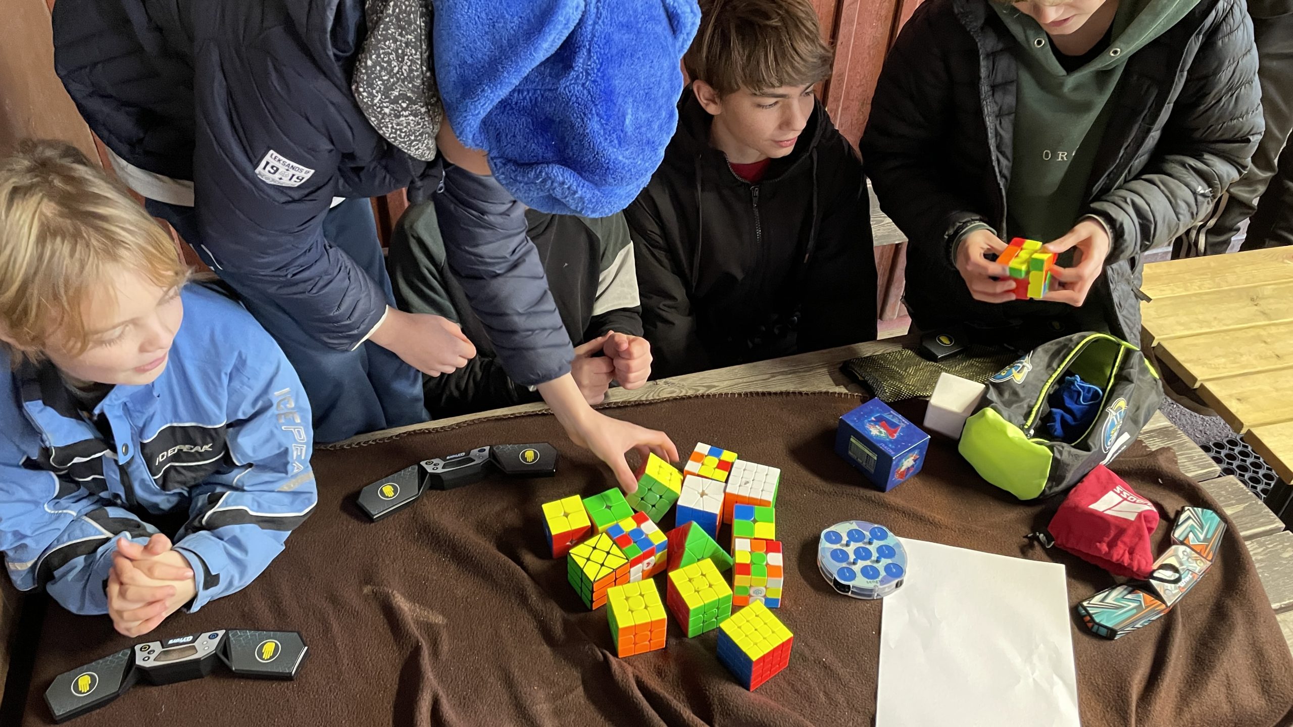 En hög med ett tiotal kuber i olika former ligger på bordet framför eleverna.