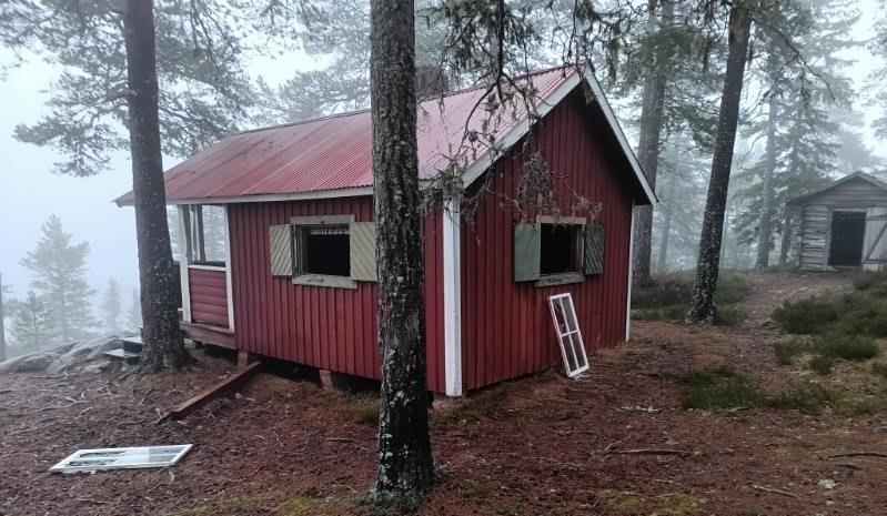 Fönsterkarmar ligger på marken utanför stugan
