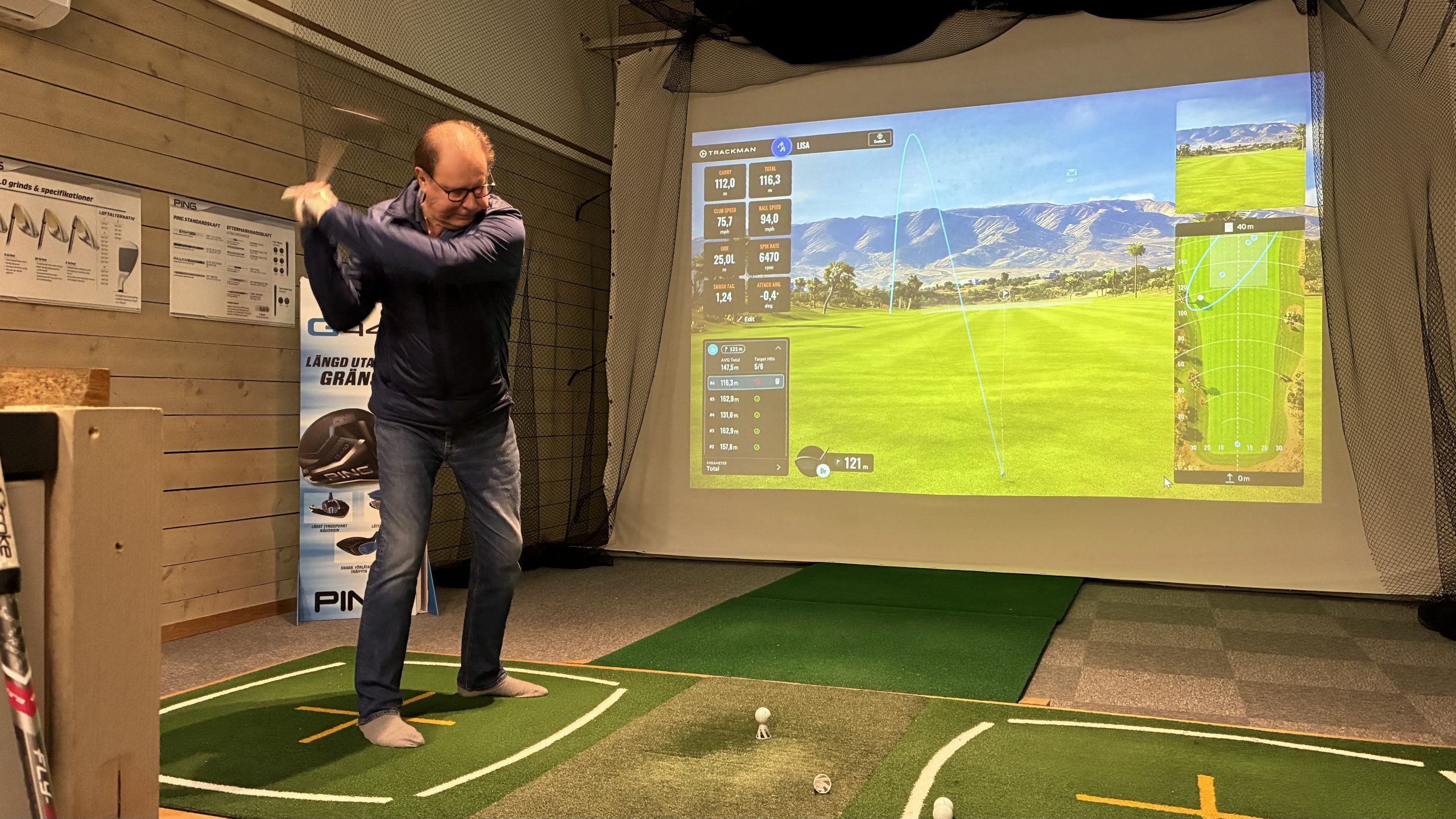 Man svingar klubba mot boll i golfsimulator