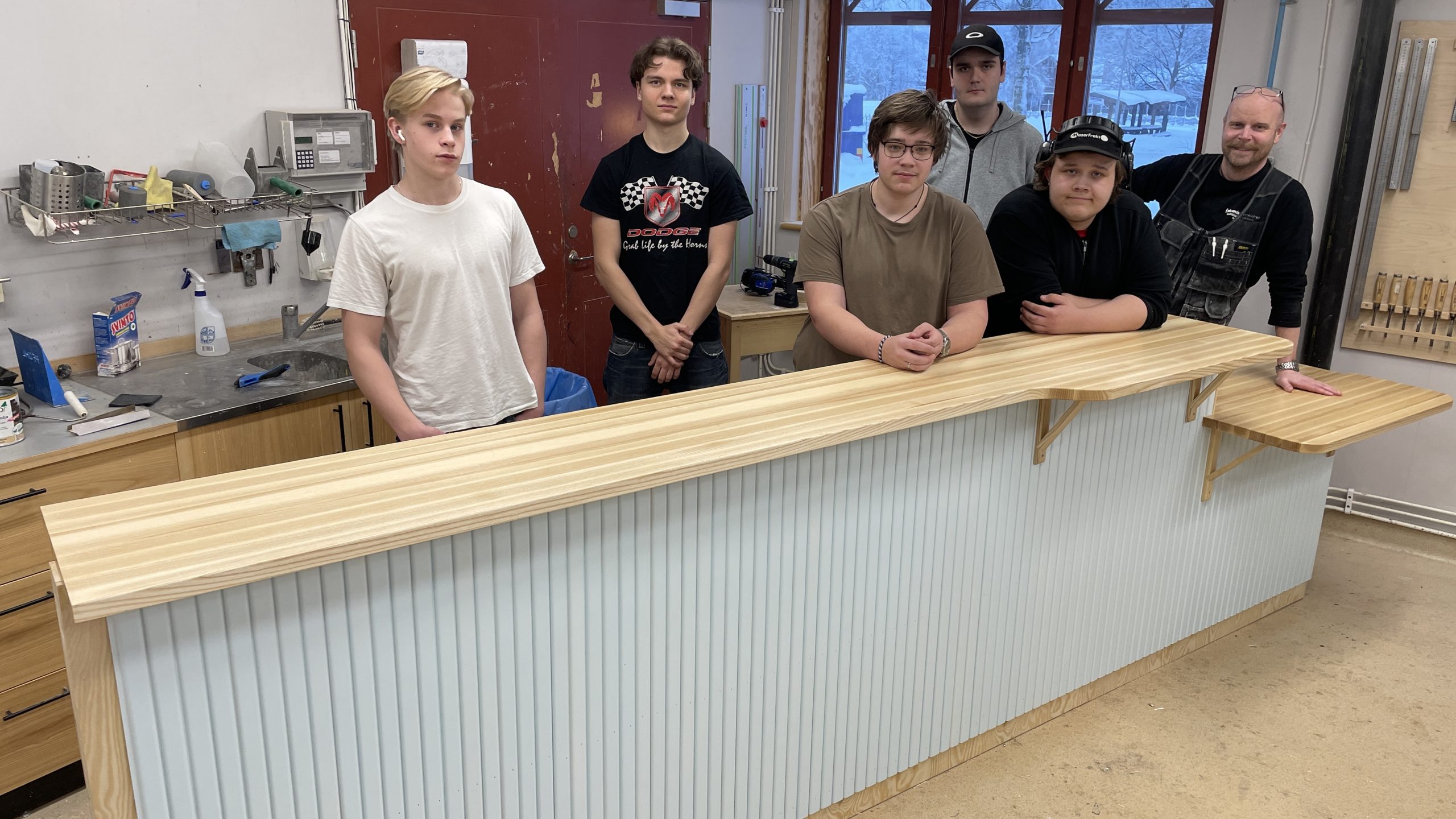 Elever och deras lärare uppradade bakom receptionsdisk trä