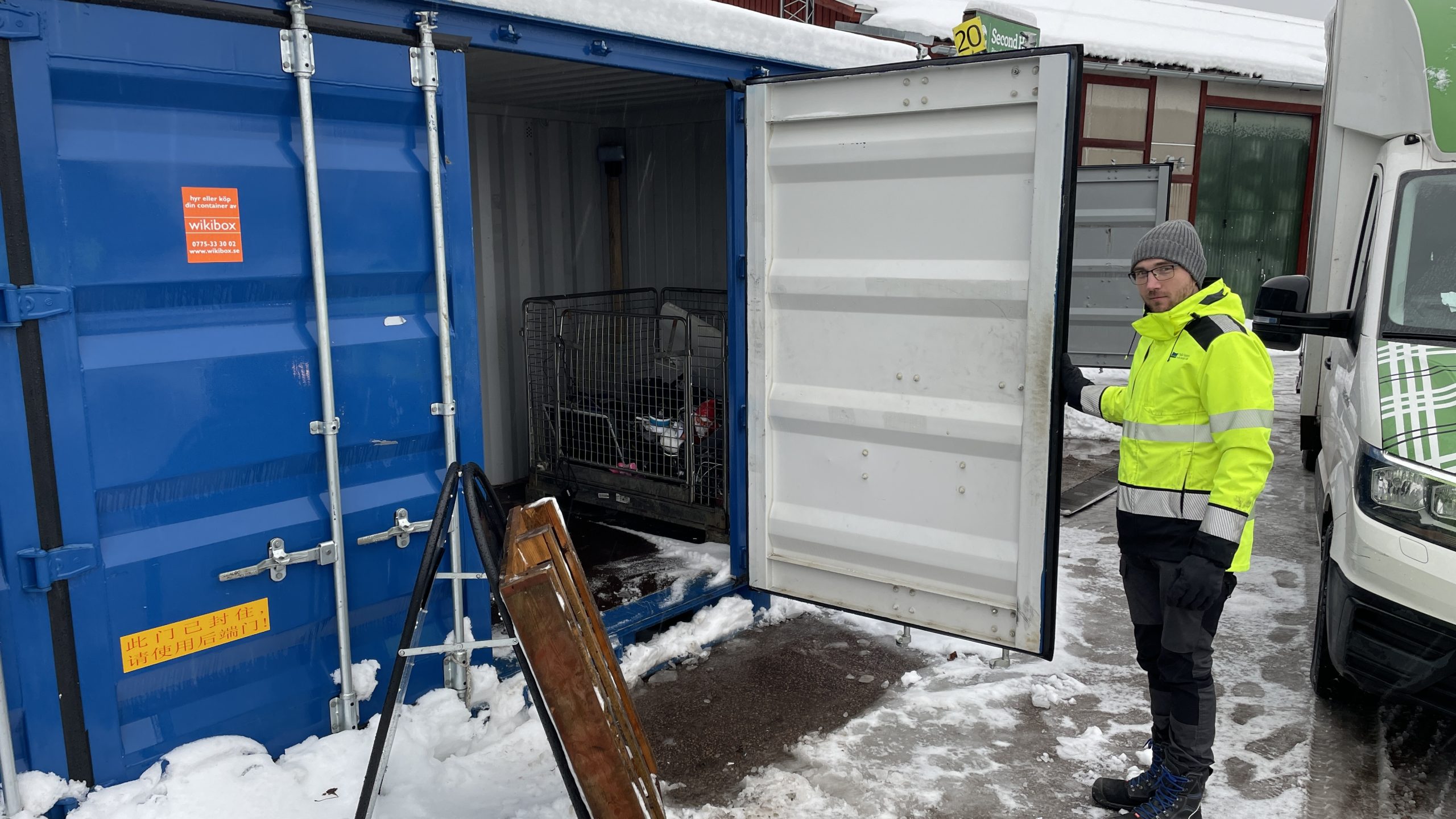 Driftchefen Joakim Fernström håller upp dörren till en container där det finns en korg för elektronikapparater.