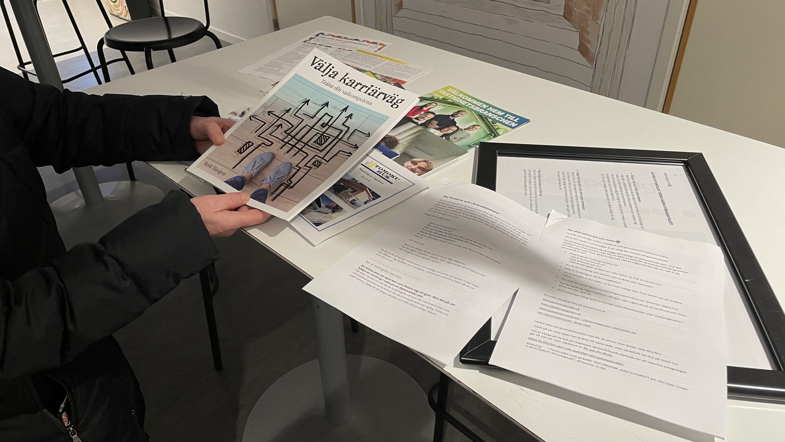 Broschyrer, foldrar och checklistor på ett bord.