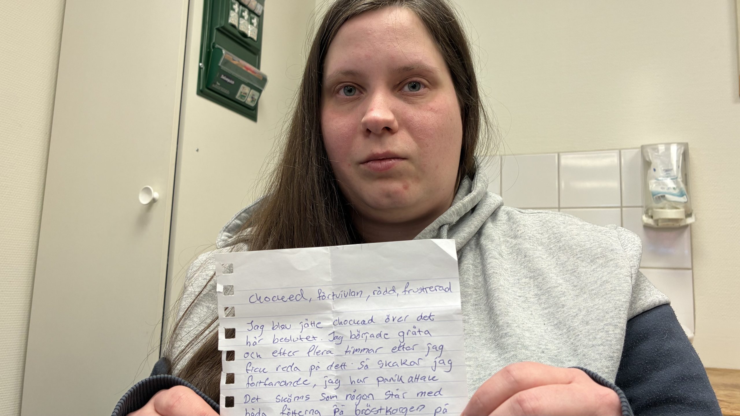 Linda Enlund håller upp en handskriven lapp framför kameran.