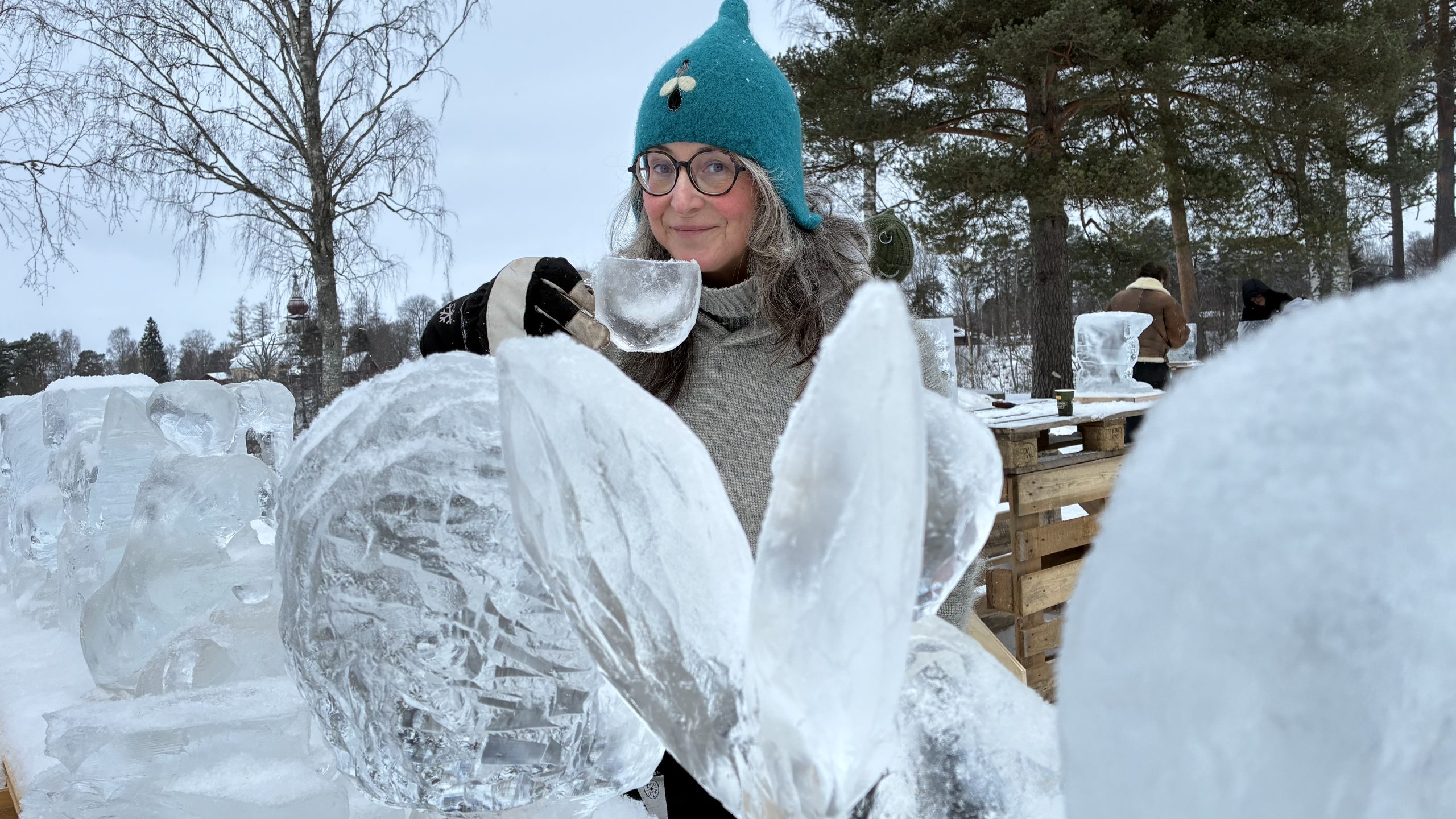 AnnaSofia håller i en kopp av is, bakom rad med isskulpturer.