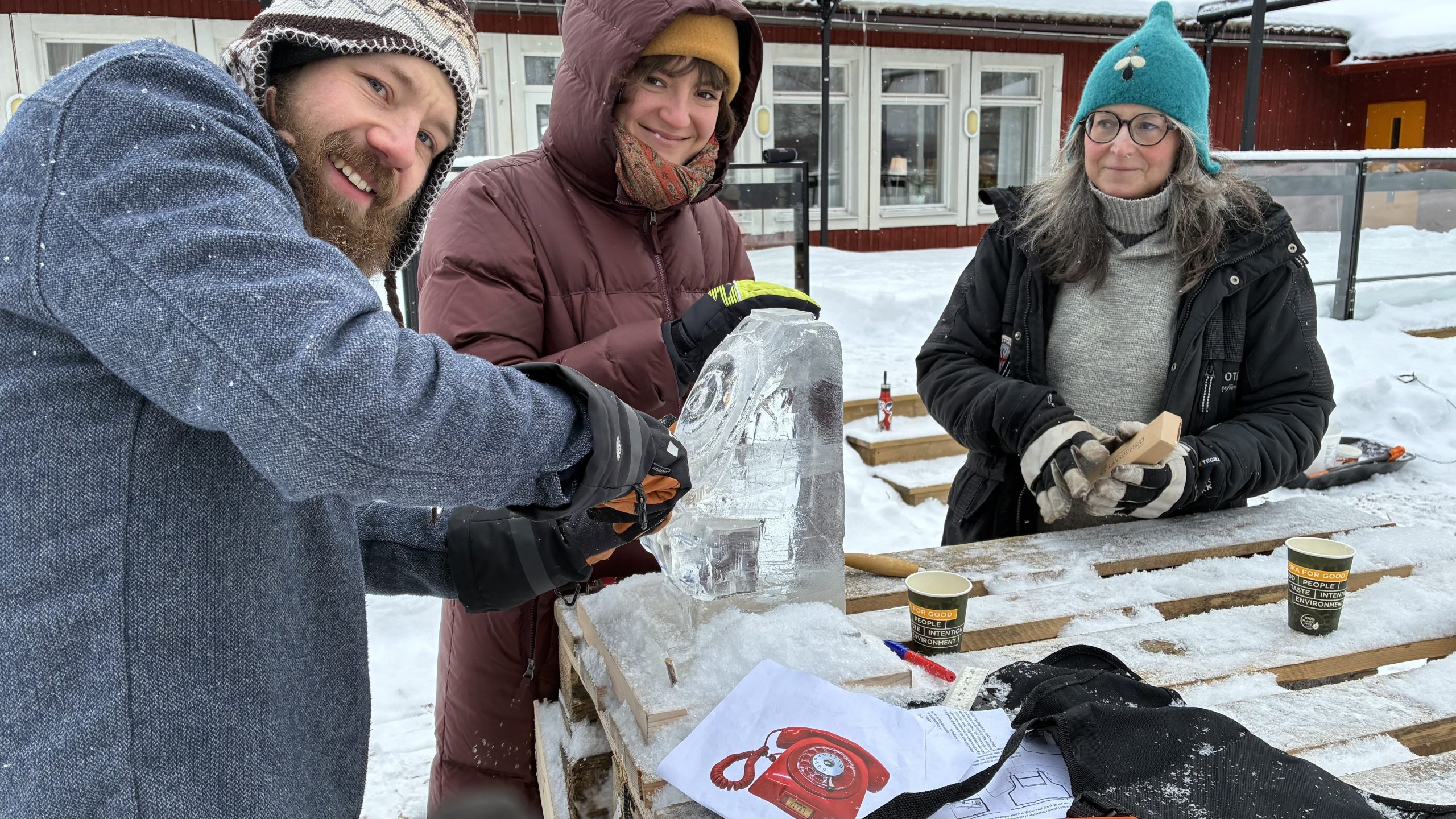 Leende personer skulpterar fram en klassisk telefon med fingerskiva och lur.