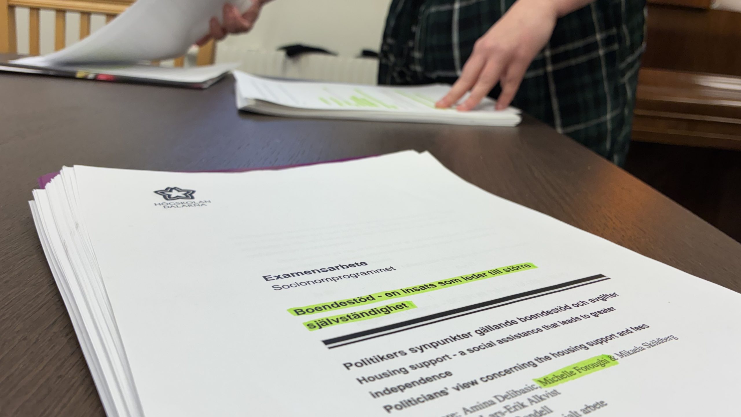 Tjock bunt med examensarbete med gula markeringar på.