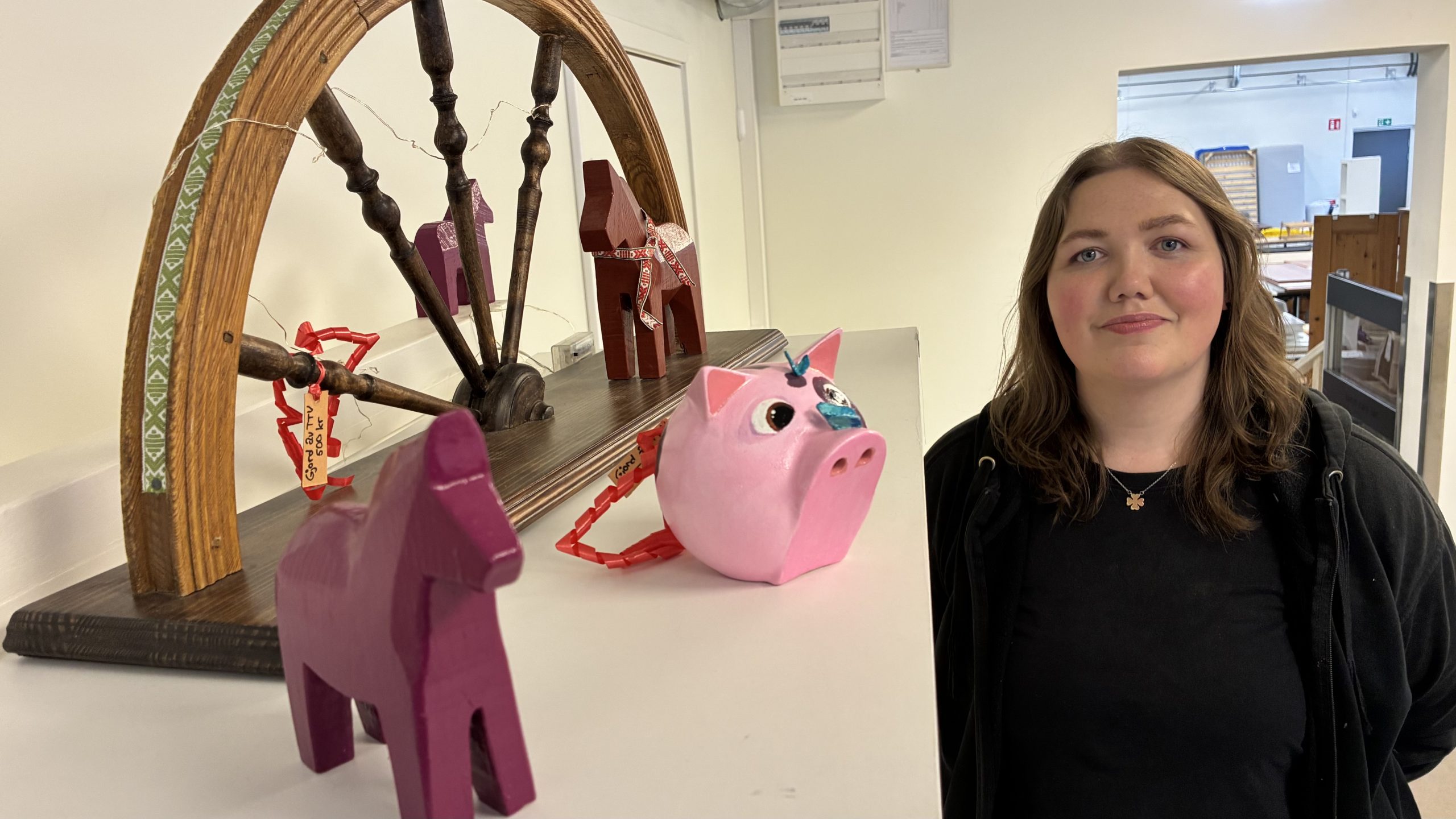 En målad spargris, en dalahäst och ett halvt hjul med kurbitsmotiv. Kreatören Elin Hinrichsen står btedvid