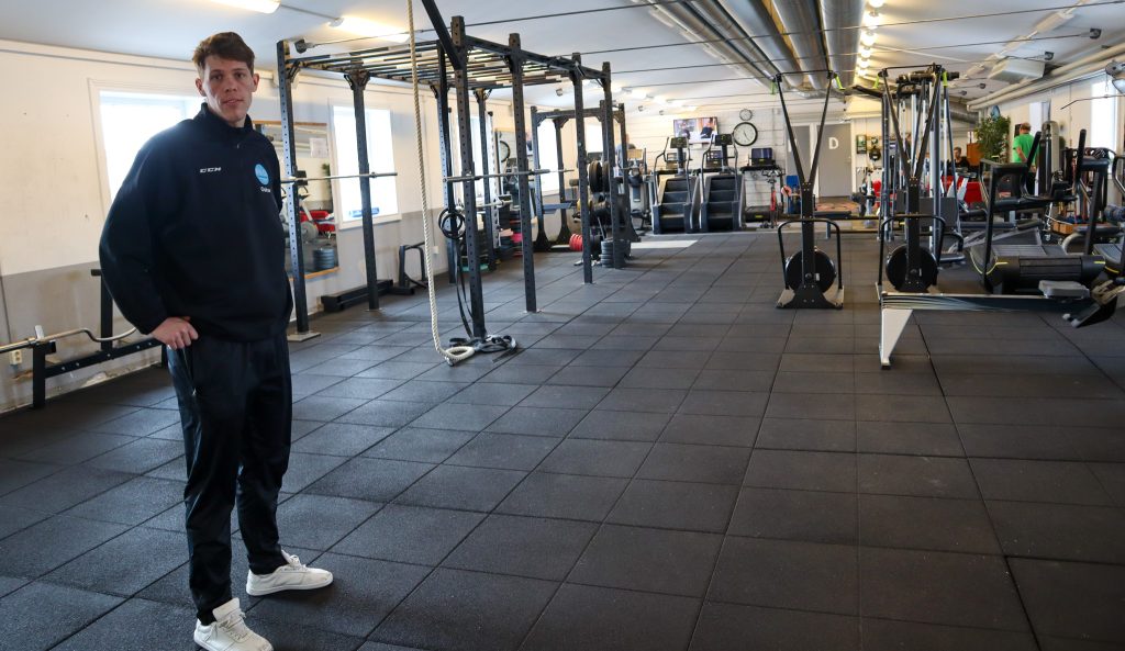 Oskar Syrén står framför maskiner på ett gym.