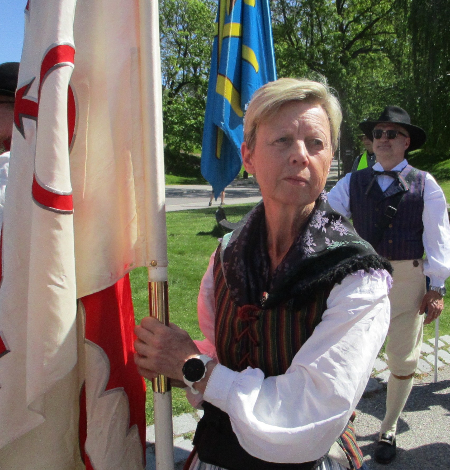 Laila Davidsson iklädd folkdräkt håller i en rödvit flagga.