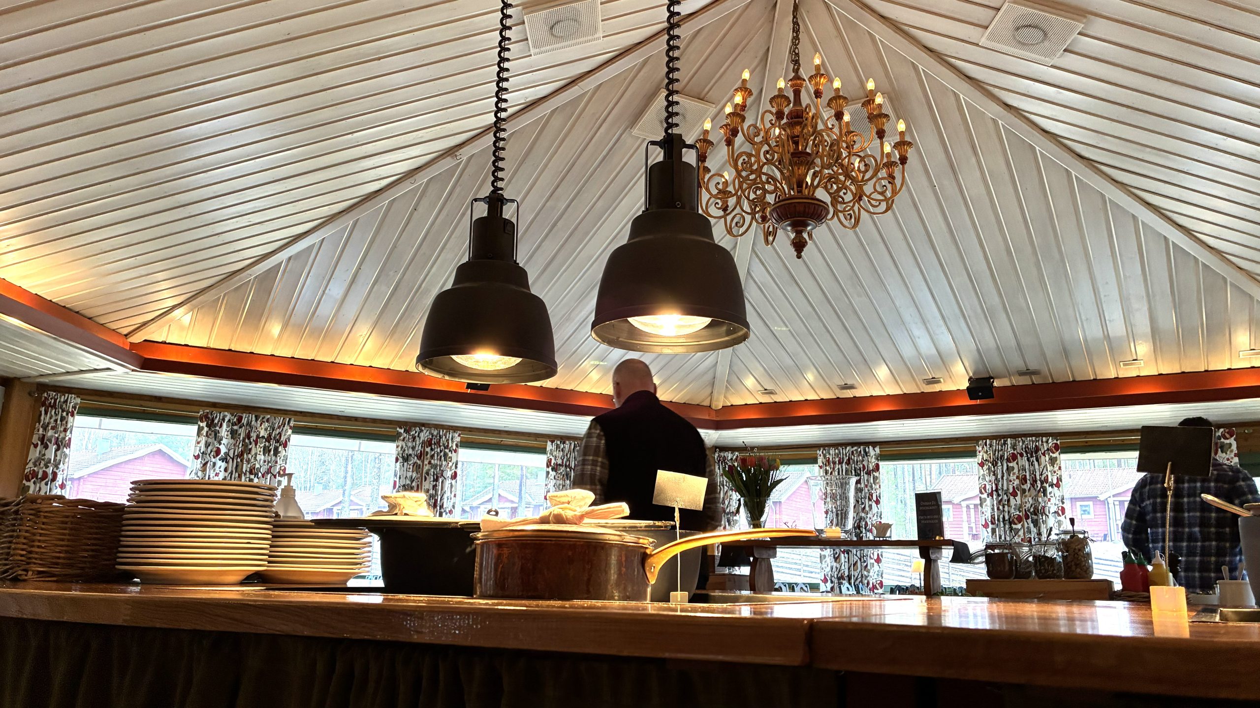 I taket på den spetsiga rotundan där maten hämtas hänger en stor lampkrona. Närmast kameran syns buffébordet med varmrätterna.