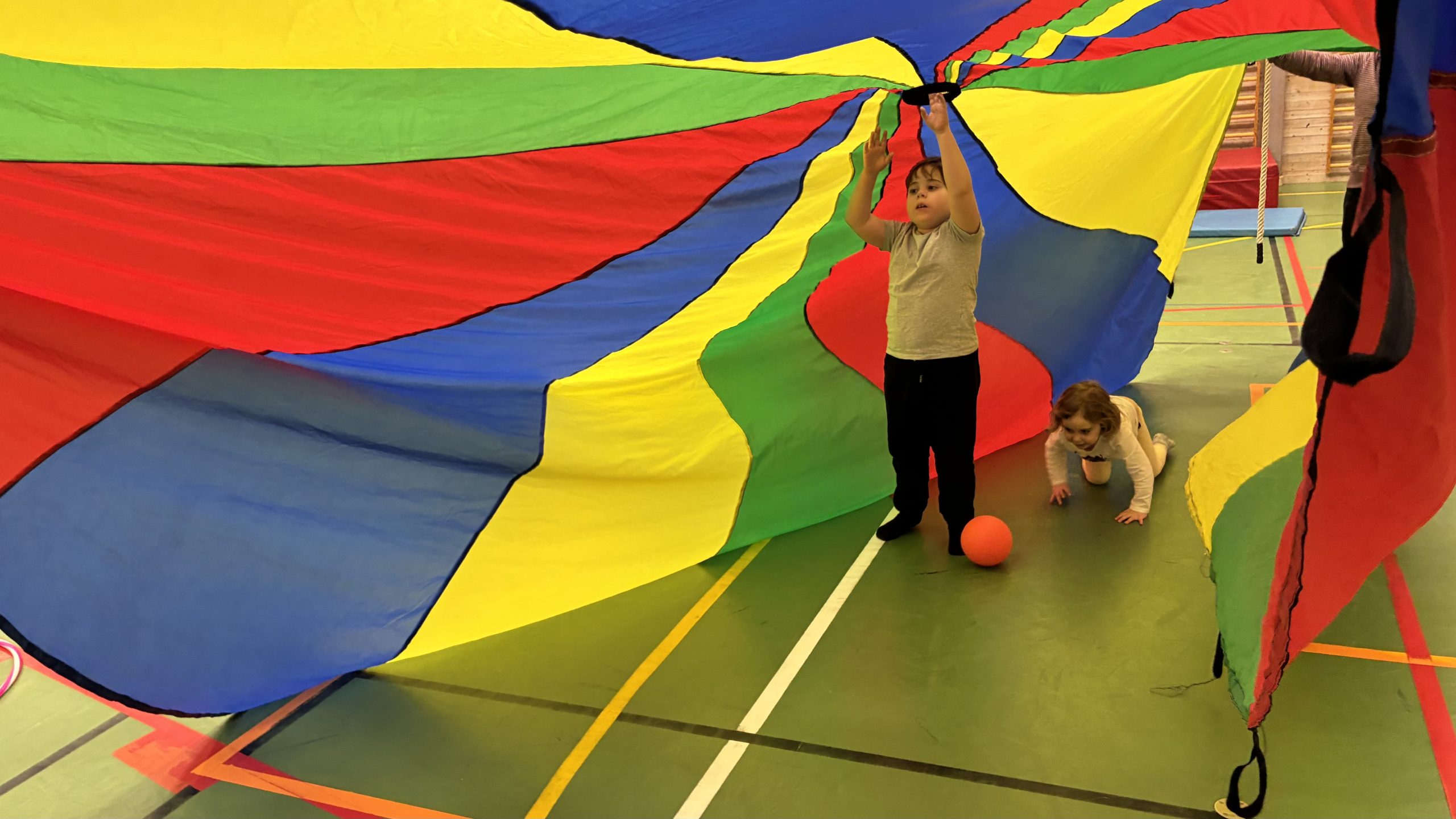 En färgglad "tältduk" hålls upp av vuxna i båda ändar, och så får barnen springa igenom.