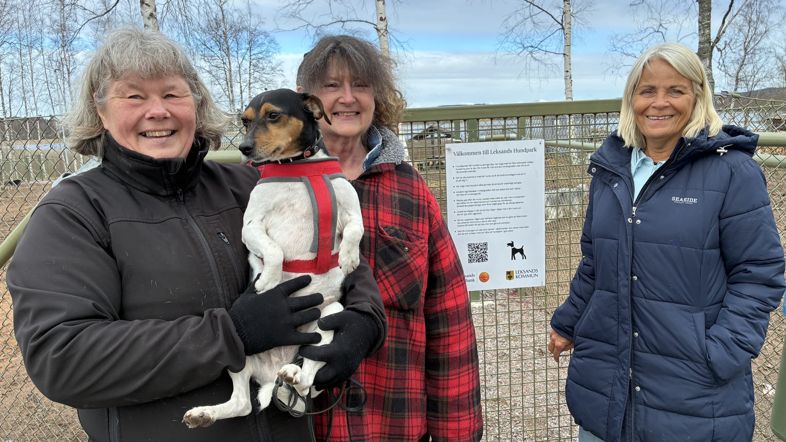 Tre personer och en hund står uppställda framför ingången och informationsskylten.