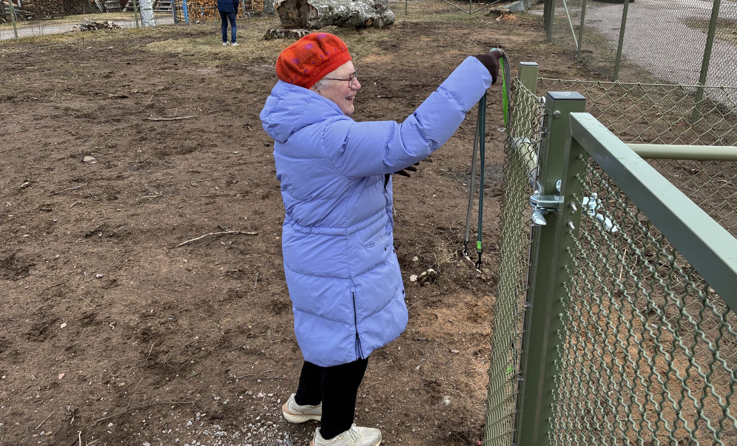 Leende kvinna hänger koppel på staketstolpe.