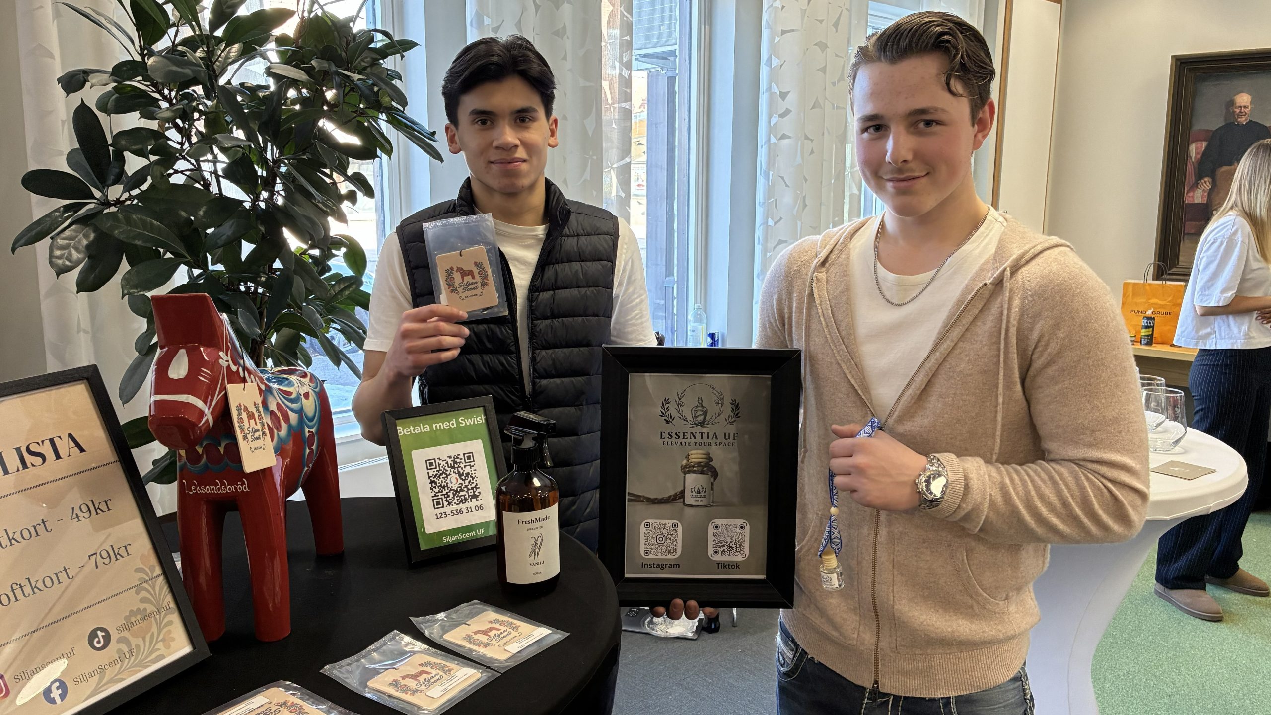 dalahäst på bordet, två gymnasiekillar håller fram doftgranar och små glasflaskor.