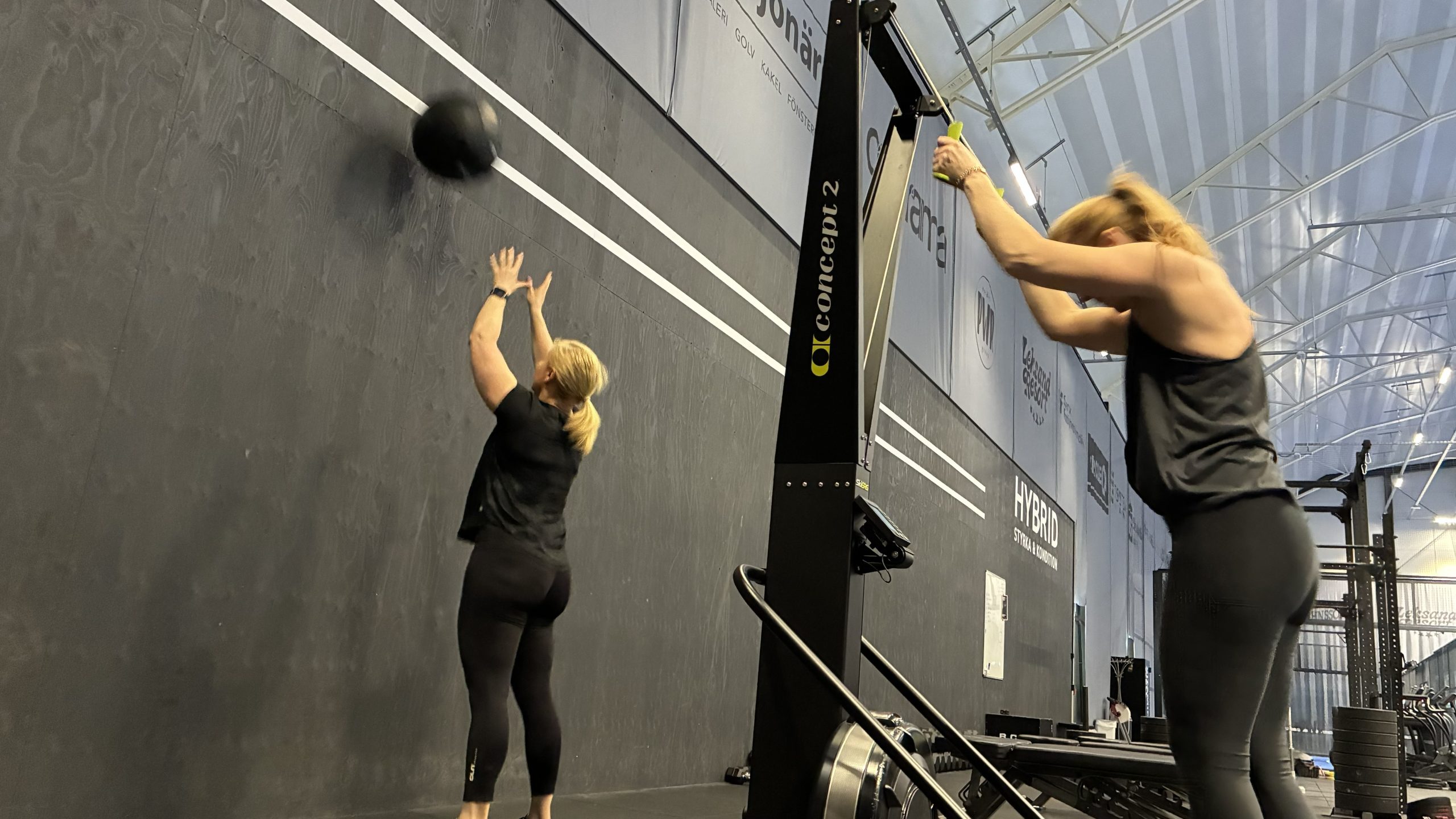 En kvinna kastar en boll mot en linje på väggen, en annan kvinna drar i en stakmaskin.