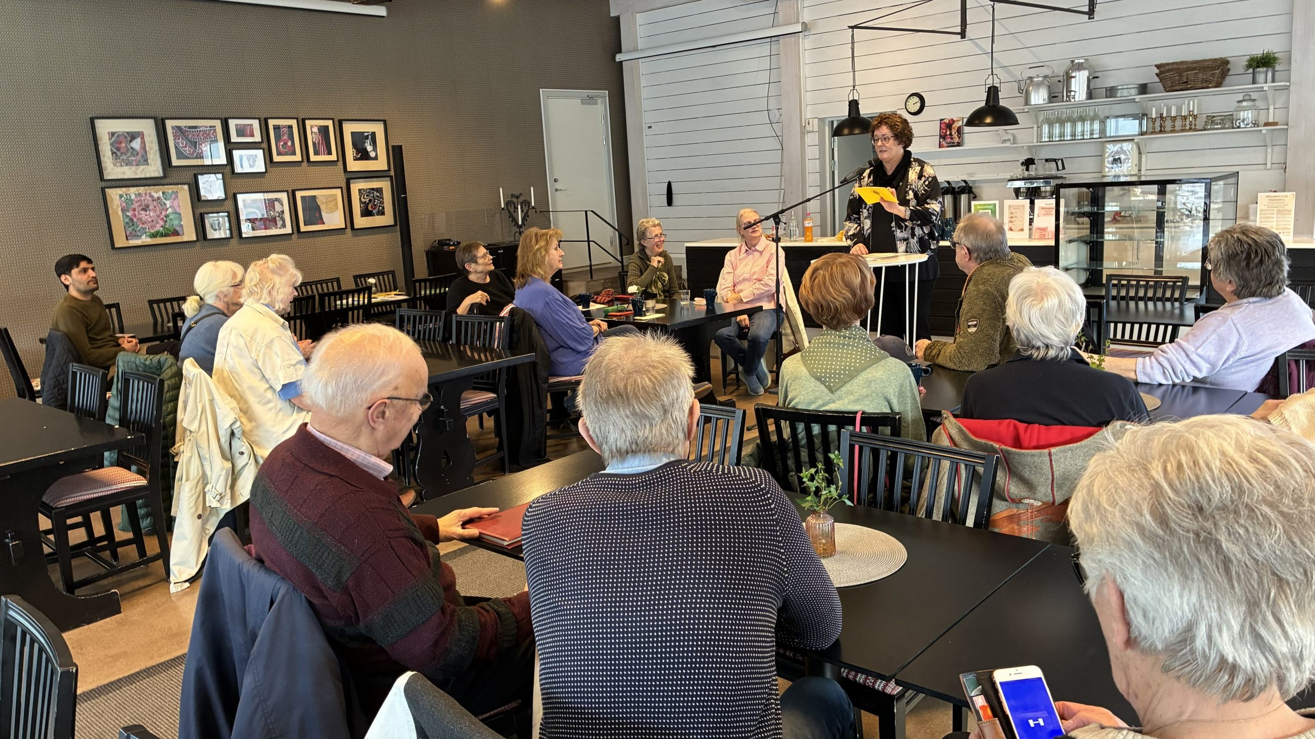 Bakhuvuden på mötesdeltagarna syns när de lyssnar på Birgitta Laszlo som talar framför gruppen.
