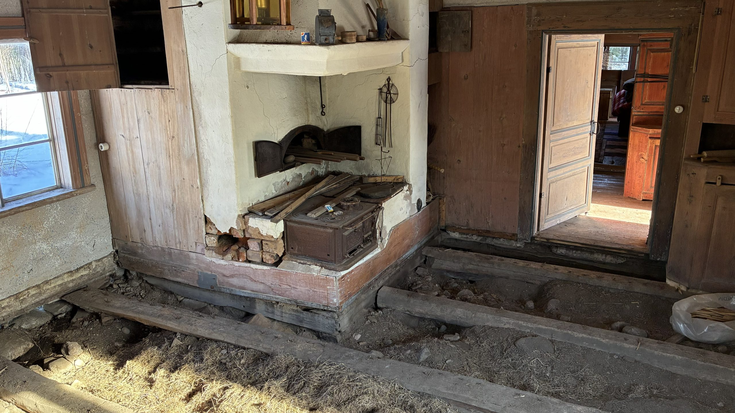 Uppbrutet golv med eldstad i bakgrunden.