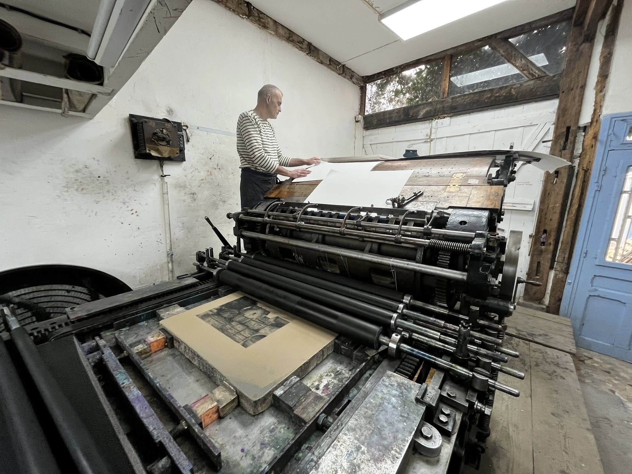 Stor tryckpressmaskin med en stenkaka som ligger redo på bänken.