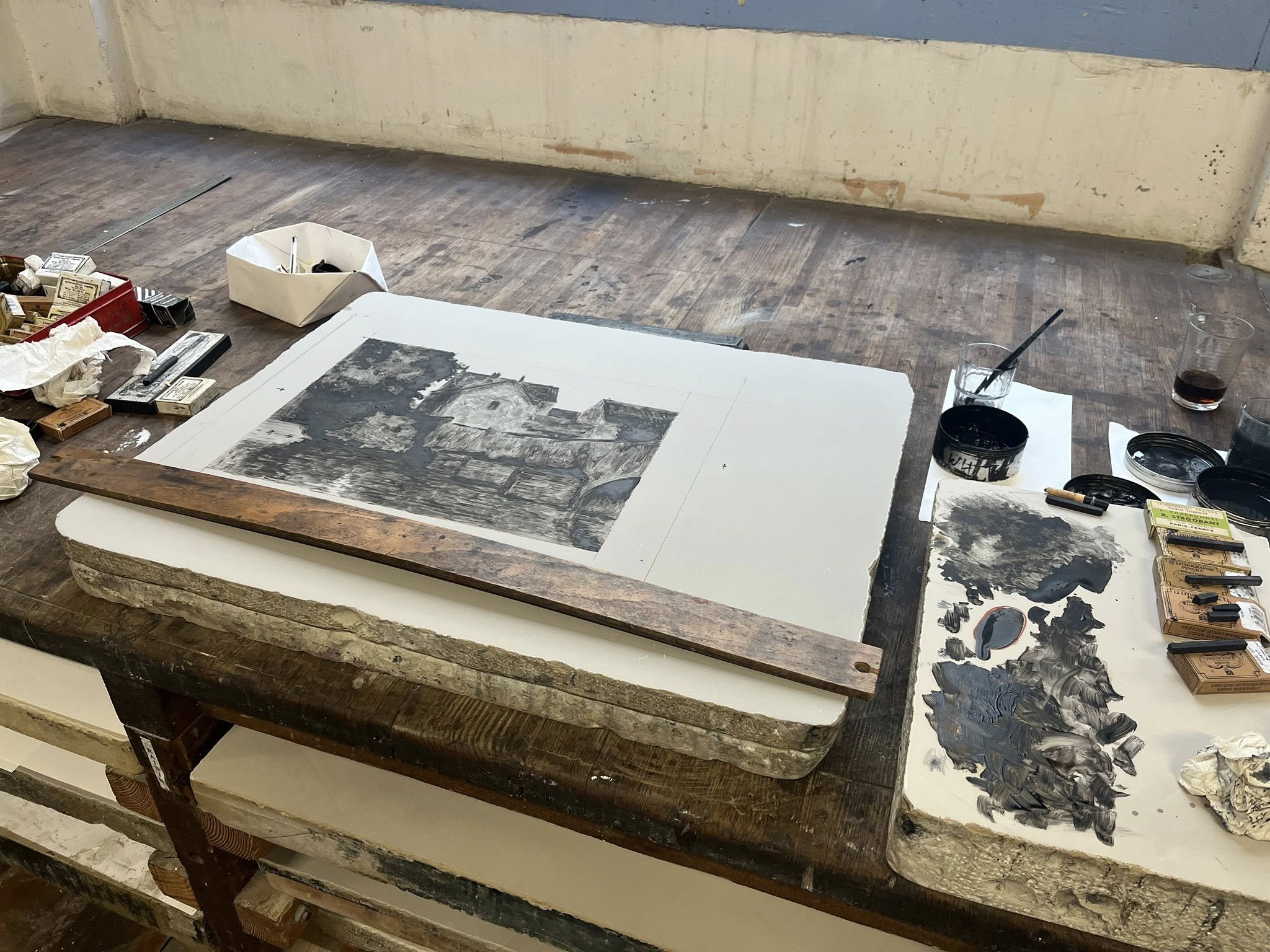 En halvfärdig målning på en stenkaka, med penslar och kritor på sidan.