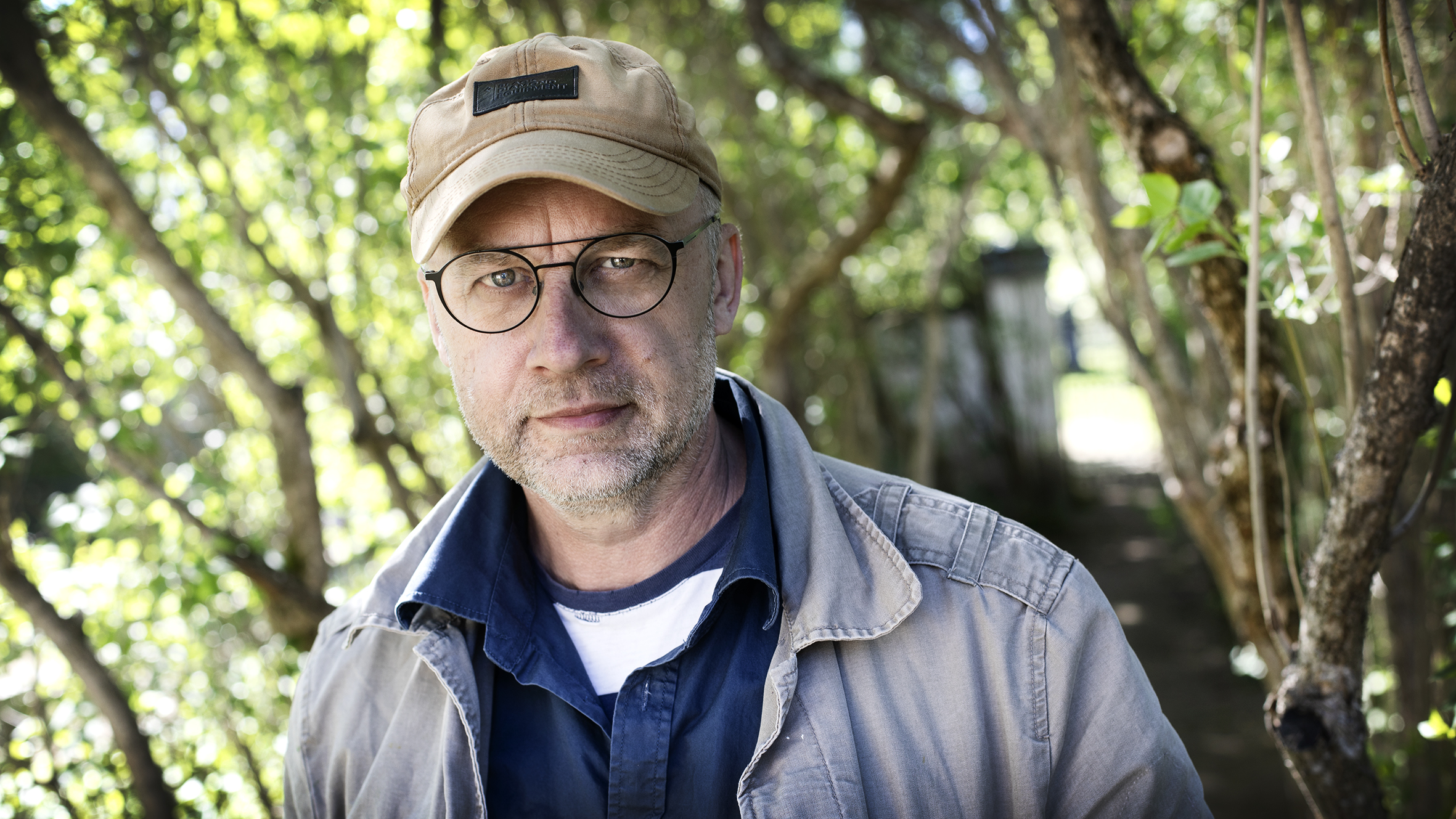 Porträttbild på Anders Ståhl i en grönskande trädgårdsmiljö.