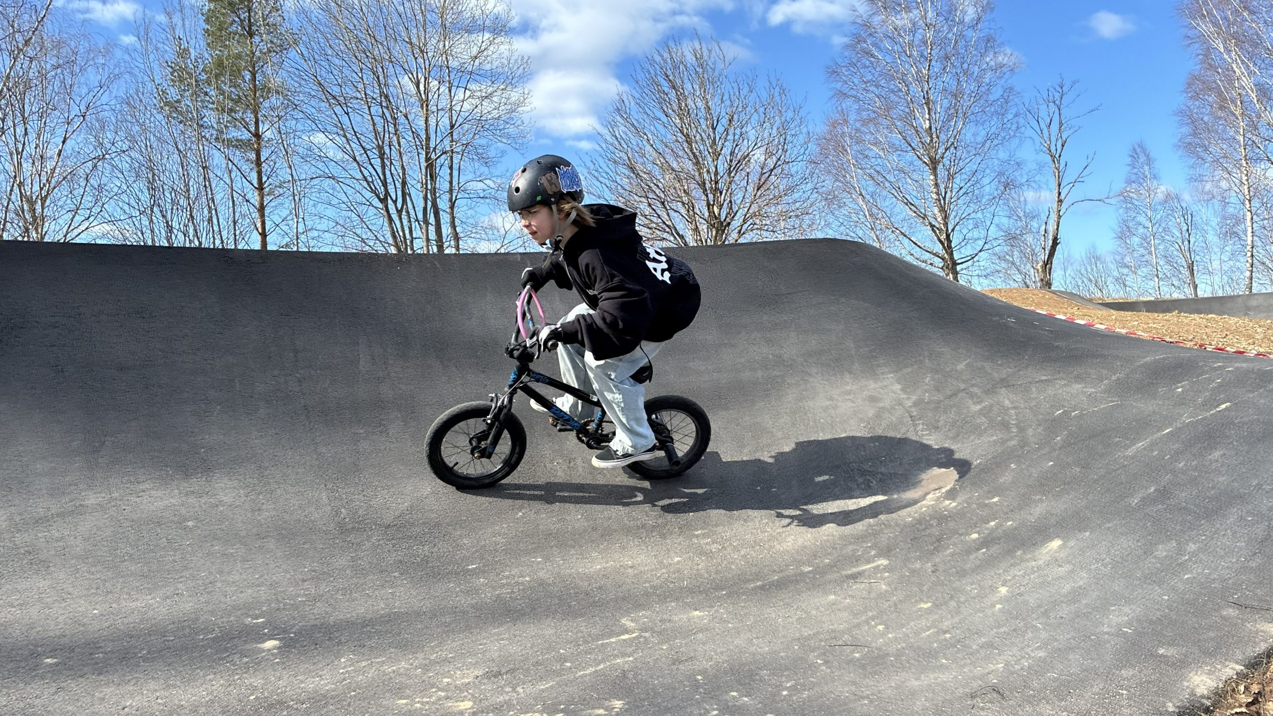 Ung cyklist cyklar genom en lutande kurva.
