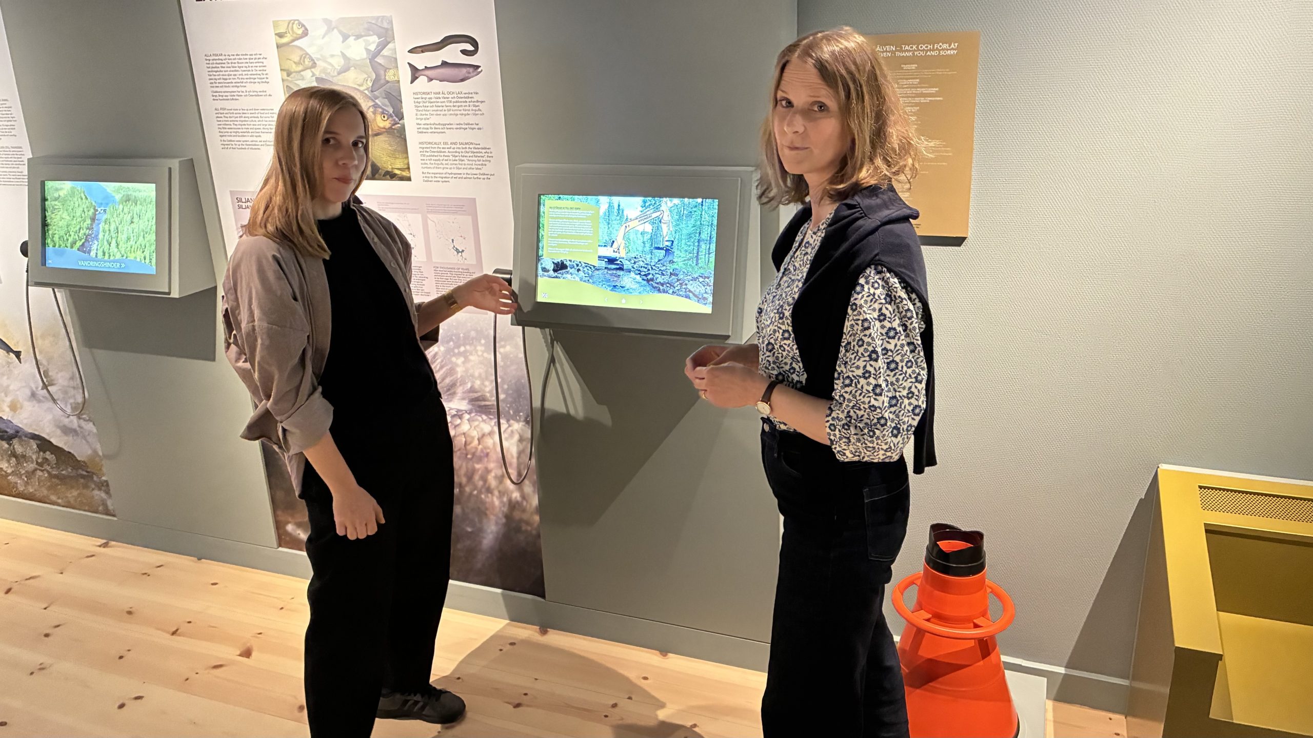 Två kvinnor visar olika delar av utställningsrummet.