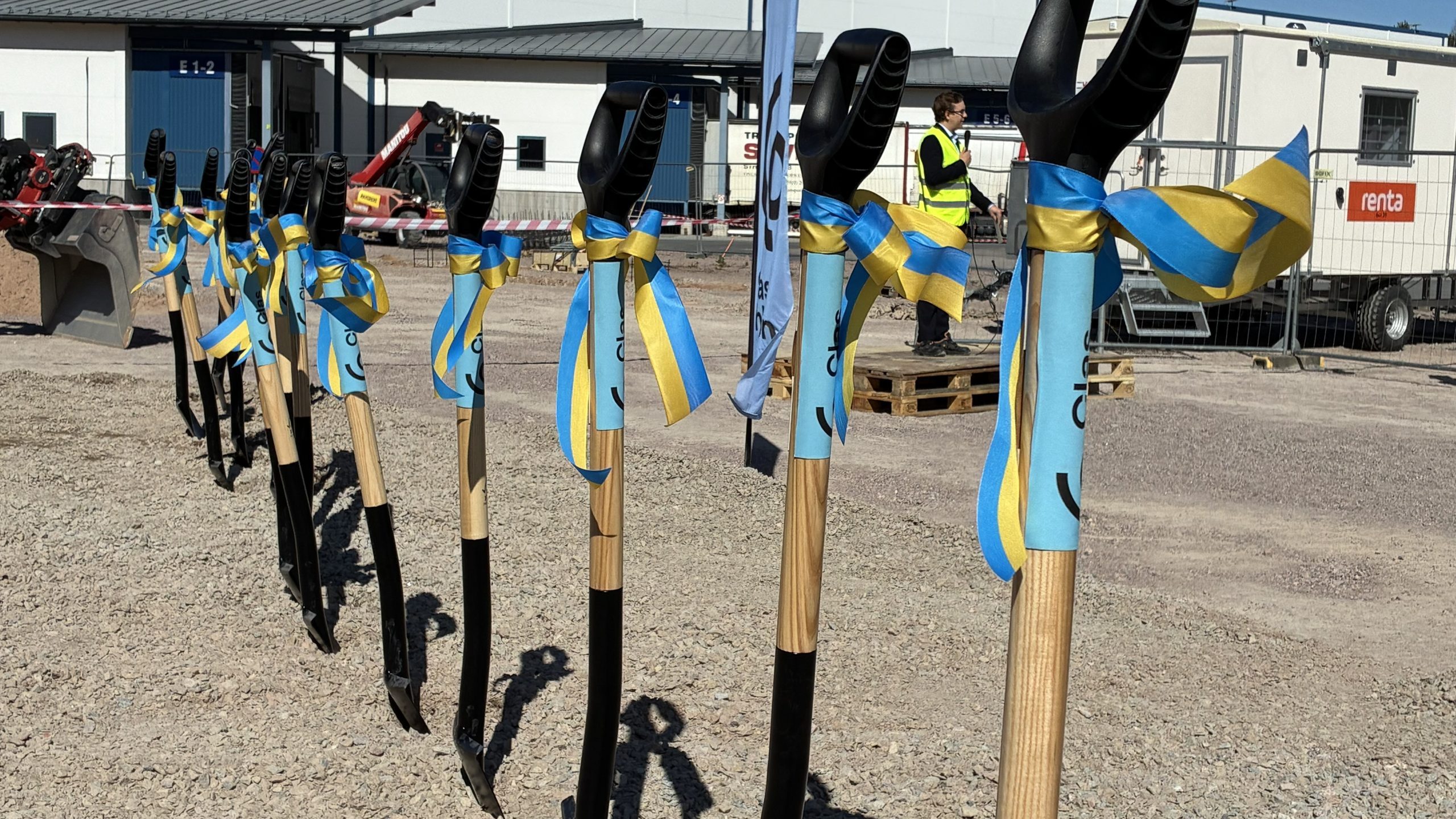 16 spadar står uppradade, i bakgrunden står en person i varselväst och håller ett ceremoniellt tal.