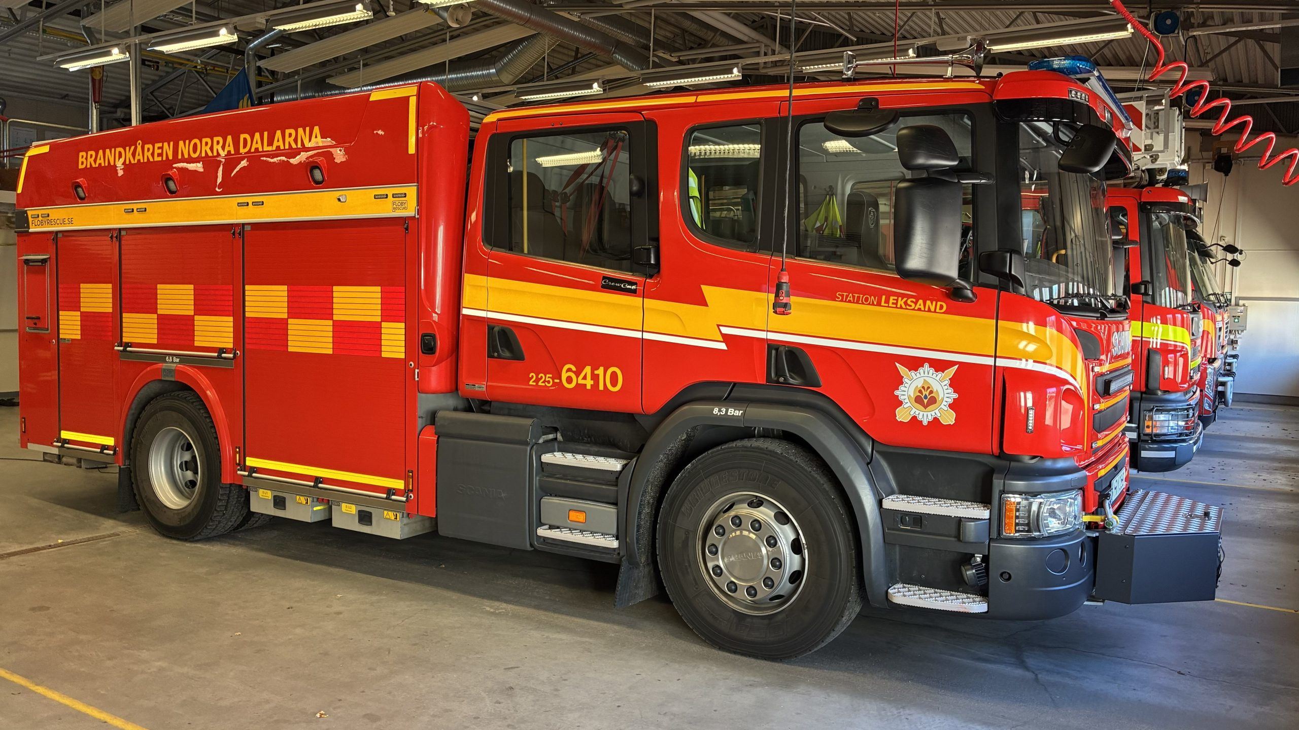 Flera brandbilar på rad inne i en maskinhall.