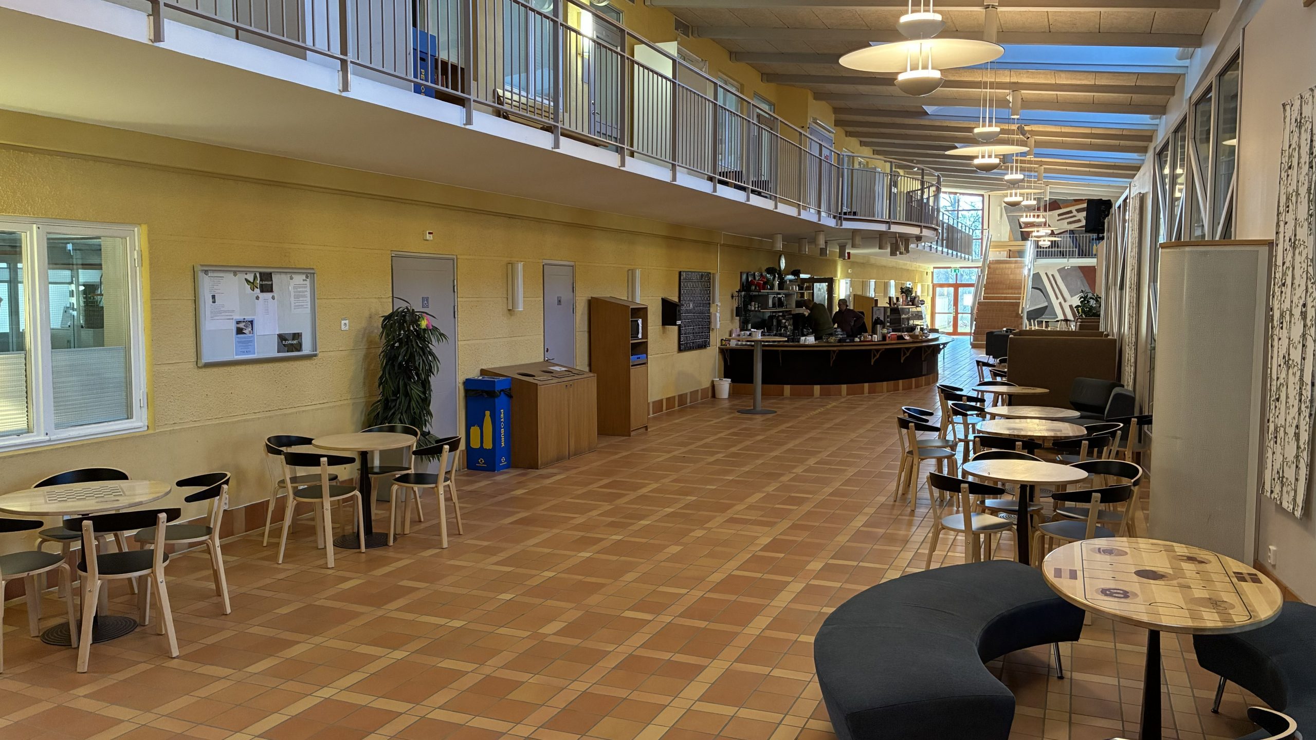 Tom korridor med bord och stolar kring cafeterian.