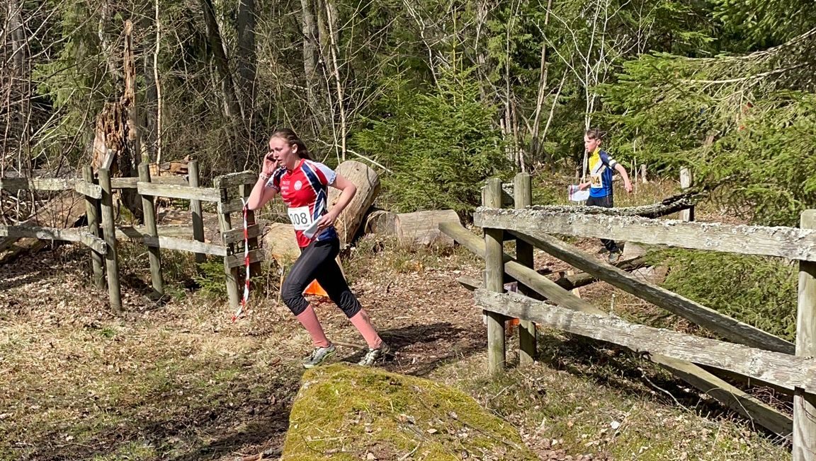 14-årig flicka springer med hög fart genom skogen, med nummerlapp på magen.