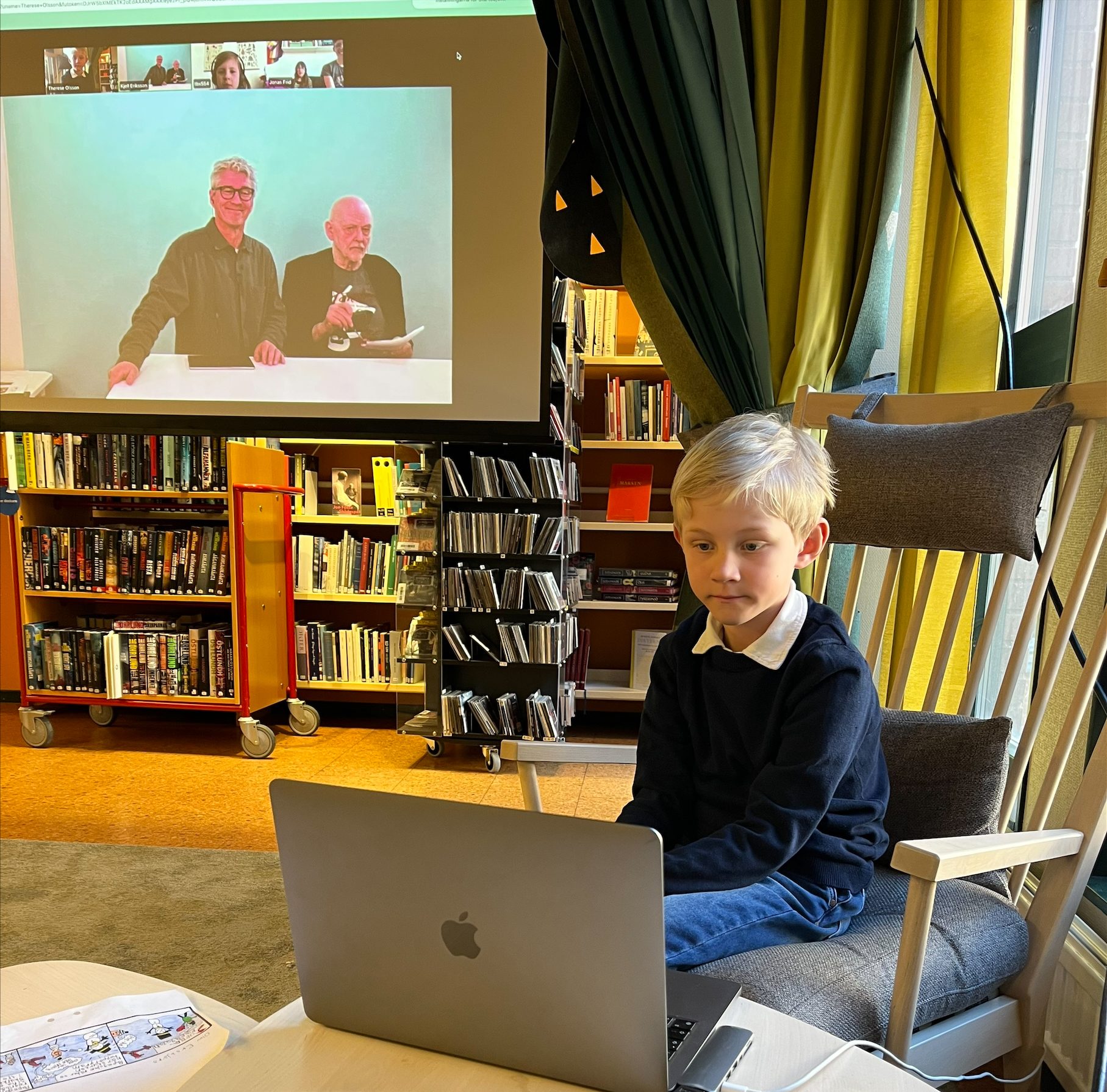 Pojke sitter framför en bärbar dator, i bakgrunden syns prisutdelarna på en stor skärm.