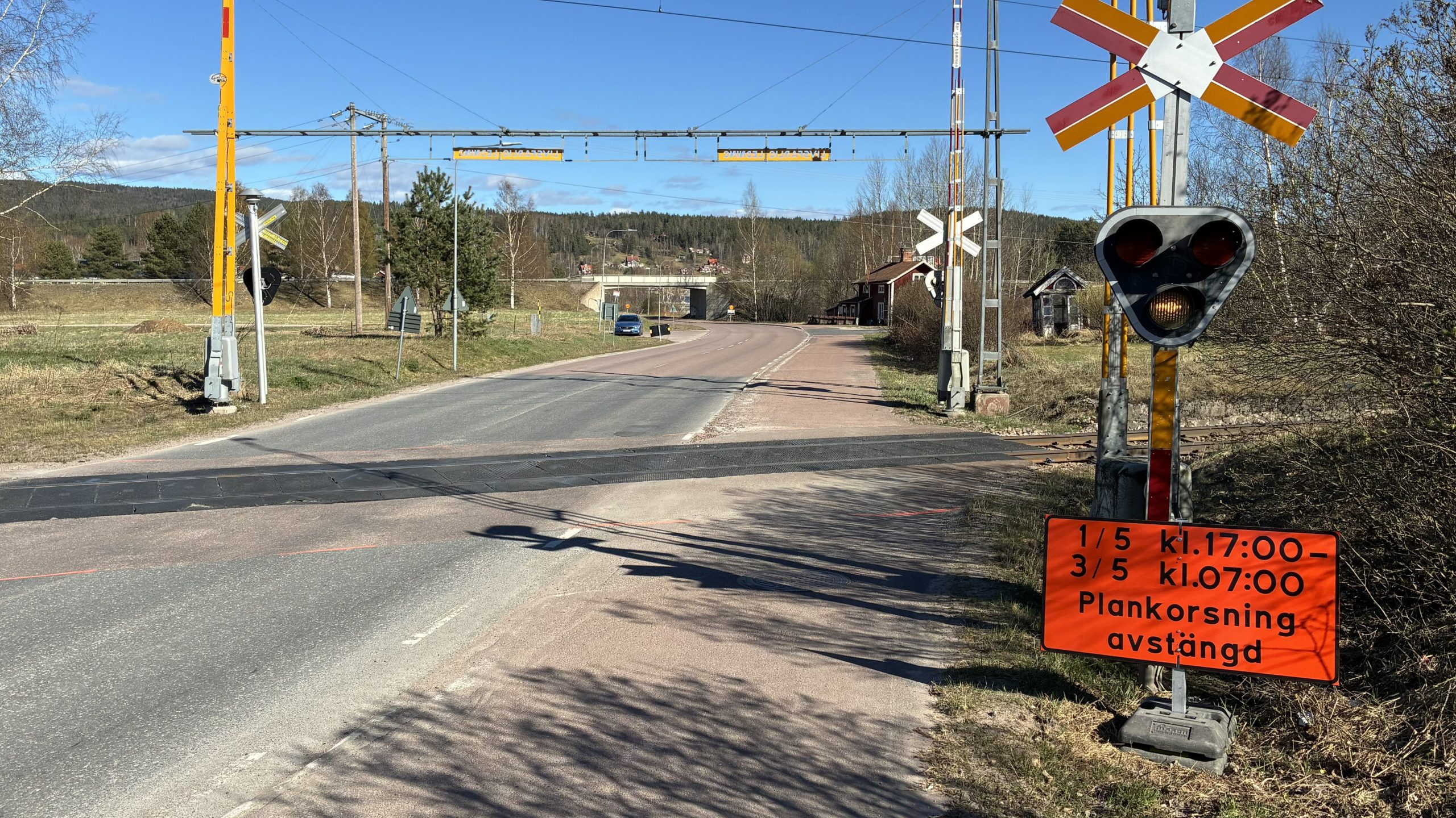 Bild på järnvägsövergången med en informationsskylt uppsatt i närheten.