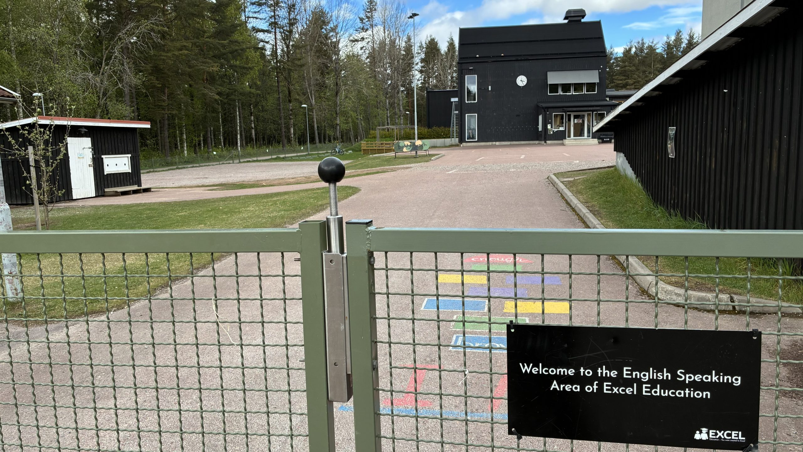 Bild på grind in till skolområdet med en text som beskriver att det ska talas engelska inne på skolområdet.