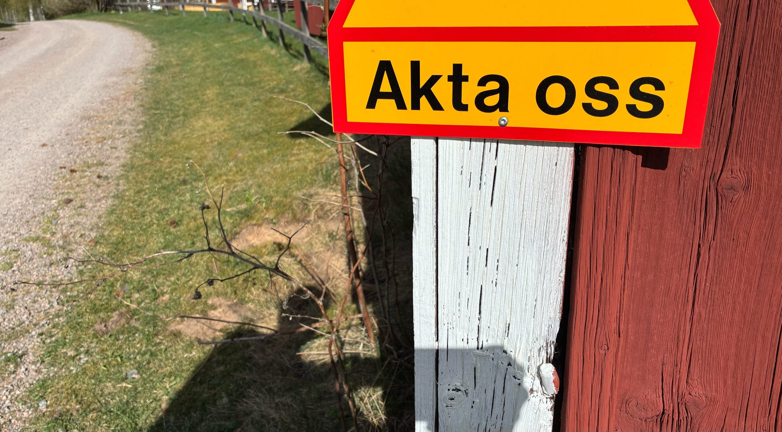 Vägskylt med texten "Akta oss", men det framgår inte av bilden vad de förbipasserade varnas för.