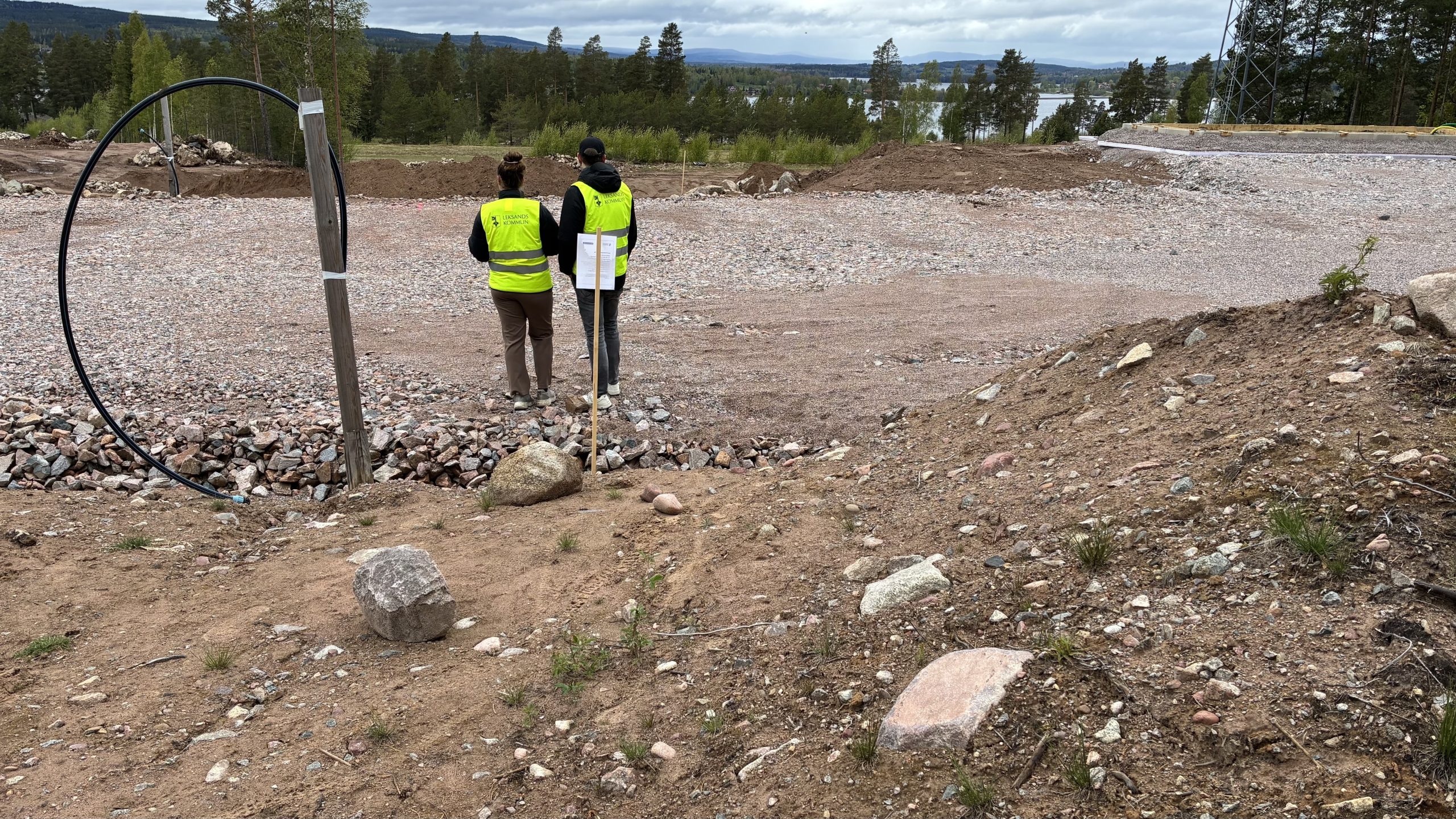 Utsikt från en hustomt med Siljan i bakgrunden. Två personer står mitt i bilden med ryggen mot kameran.