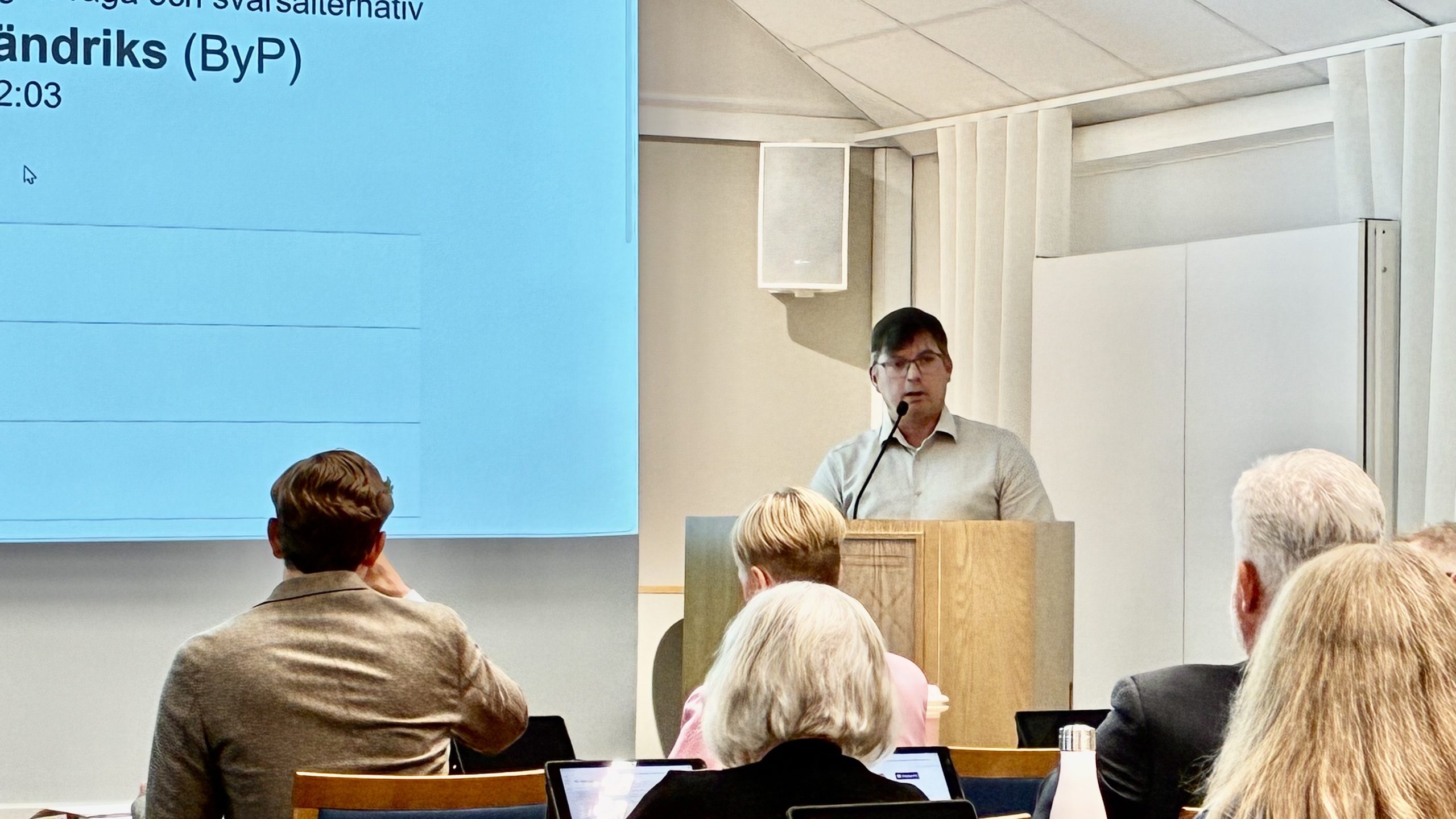 Johan Fändriks i talarstolen, några ledamöters bakhuvuden i förgrunden