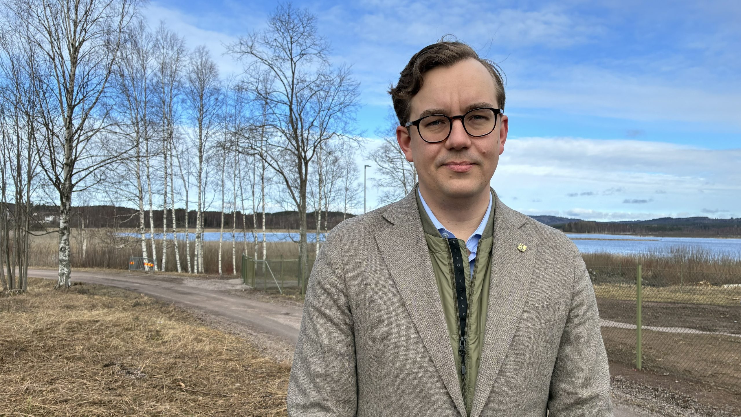Porträtt på allvarlig man som tittar in i kameran framför en sjö.
