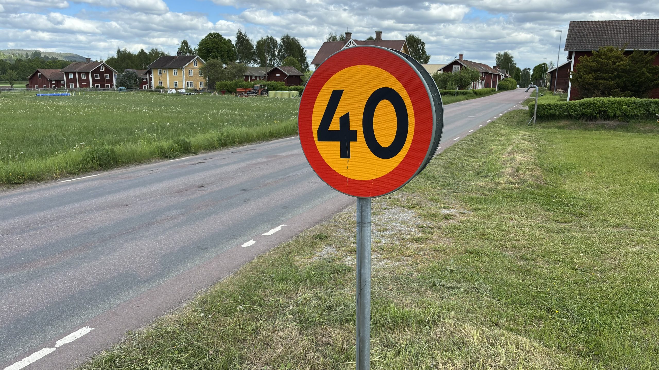 Närbild på en 40-skylt med en anonym by i bakgrunden.