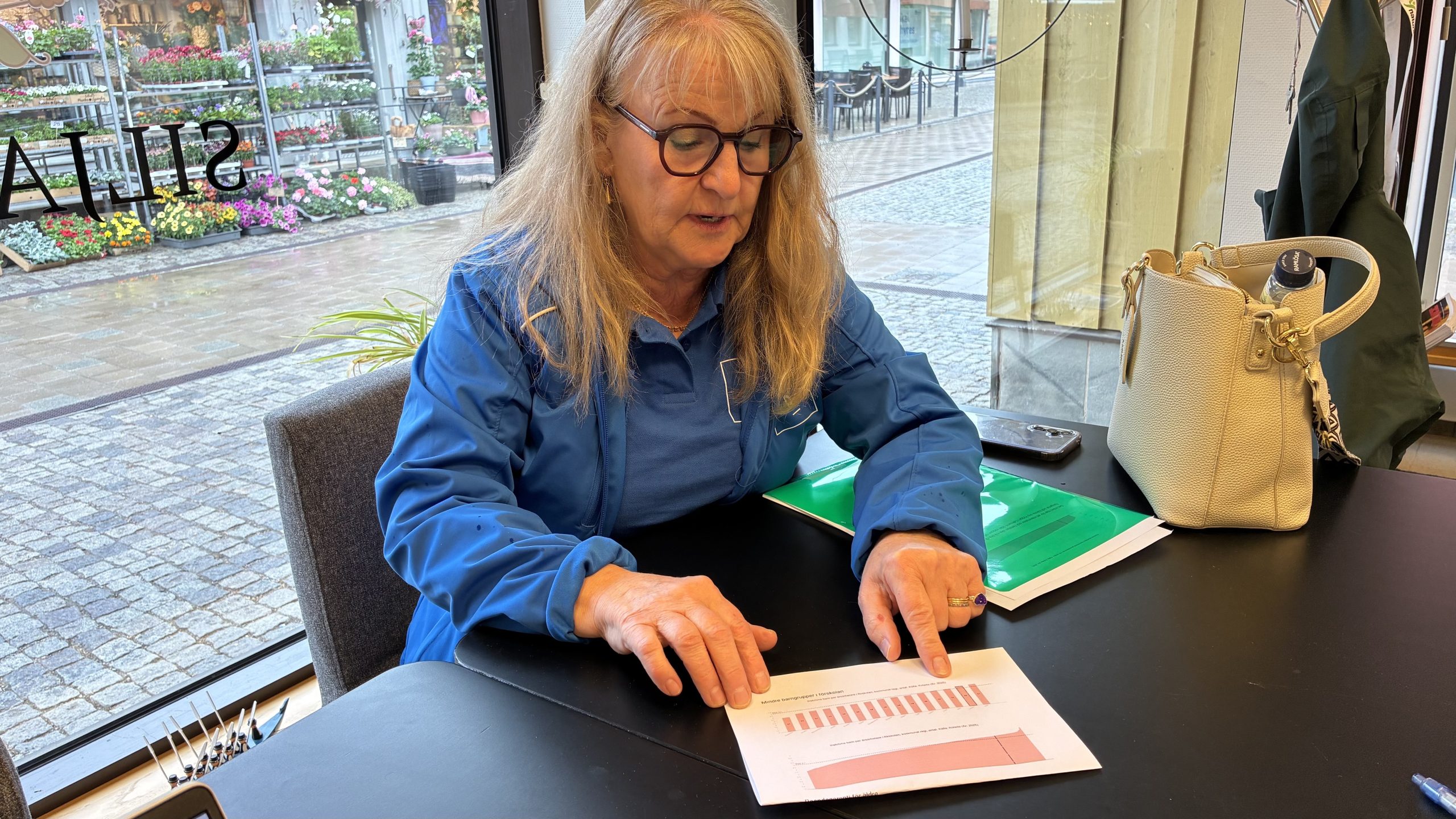 Carin Malm sitter på Siljan News redaktion och pekar på papper med stapeldiagram