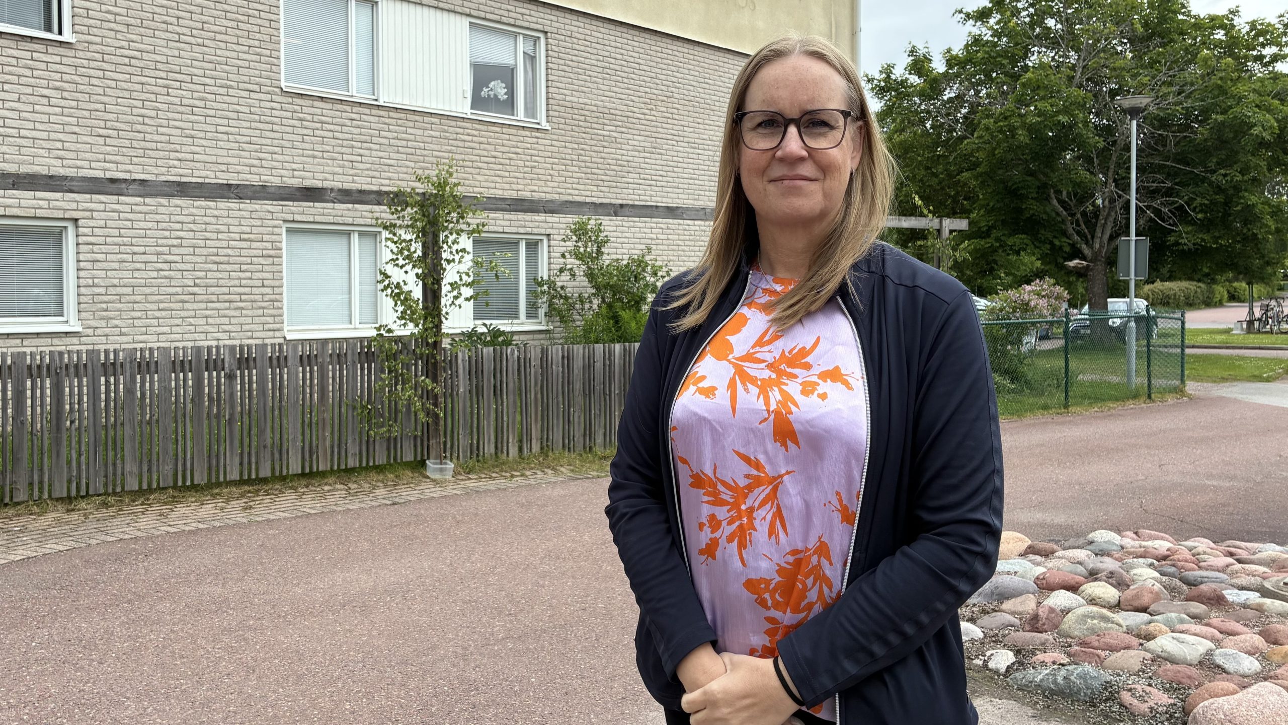 Karin MIkkonen står framför en anonym byggnad med armarna framför kroppen.