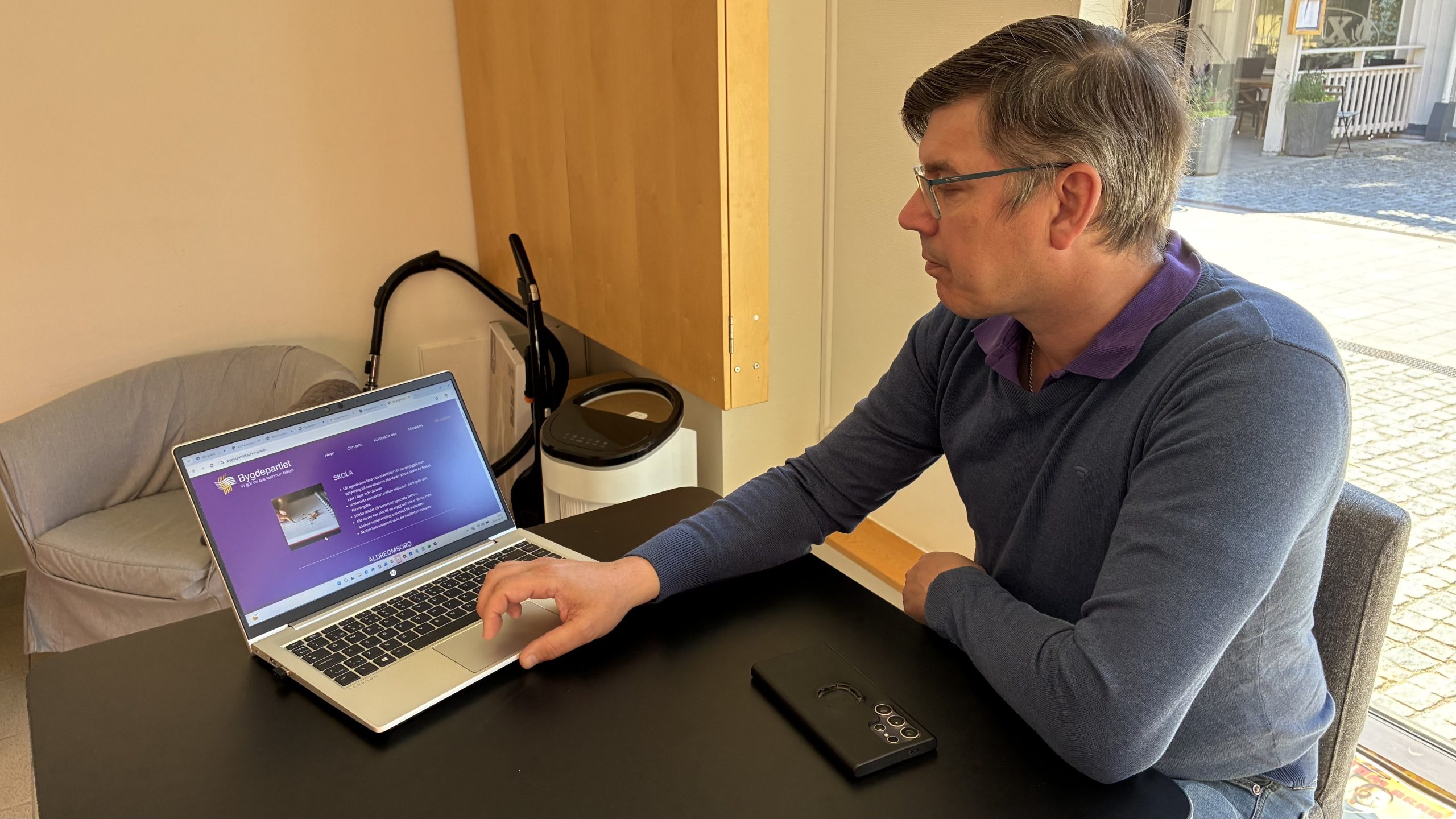 Johan Fändriks scrollar på en laptop som visar partiprogrammet, med kategorin "Skola" synlig på skärmen.