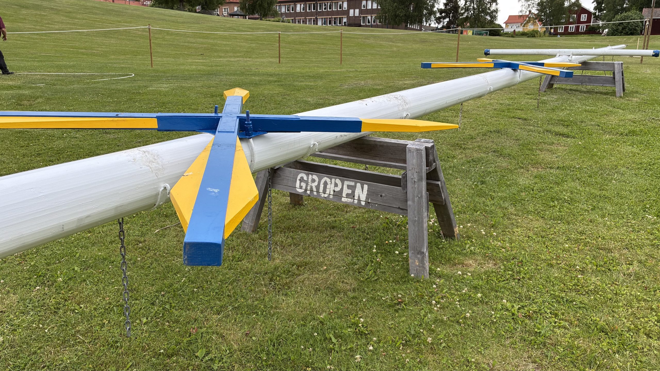 Majstång med blå-gula symboler ligger på pallbockar i en folktom Sammilsdalsgrop.