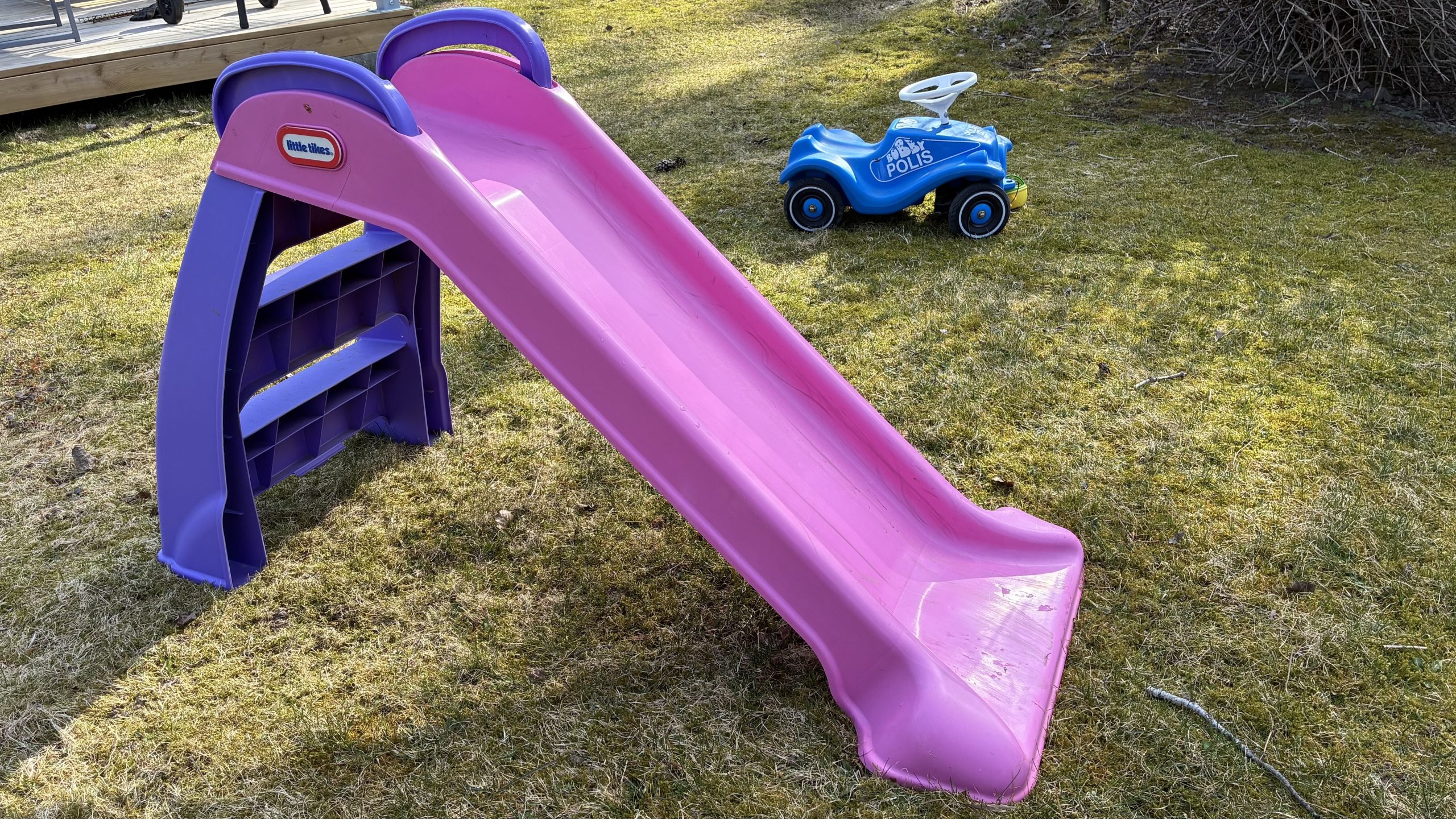 Närbild på en rutschkana och en liten blå leksaksbil målad i polismotiv.