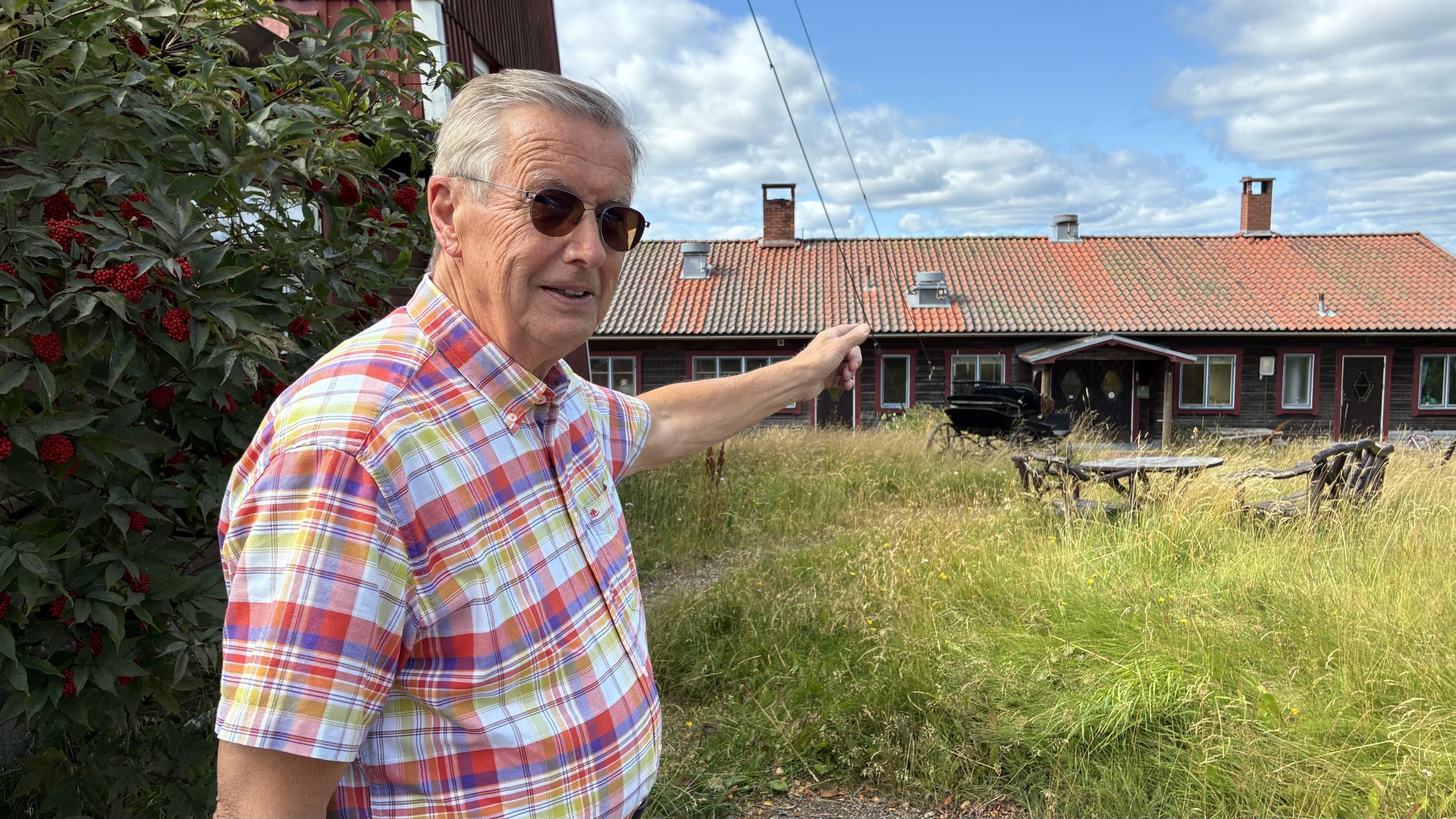 Man i rutig skjorta pekar på byggnad till höger om utkikstornet.