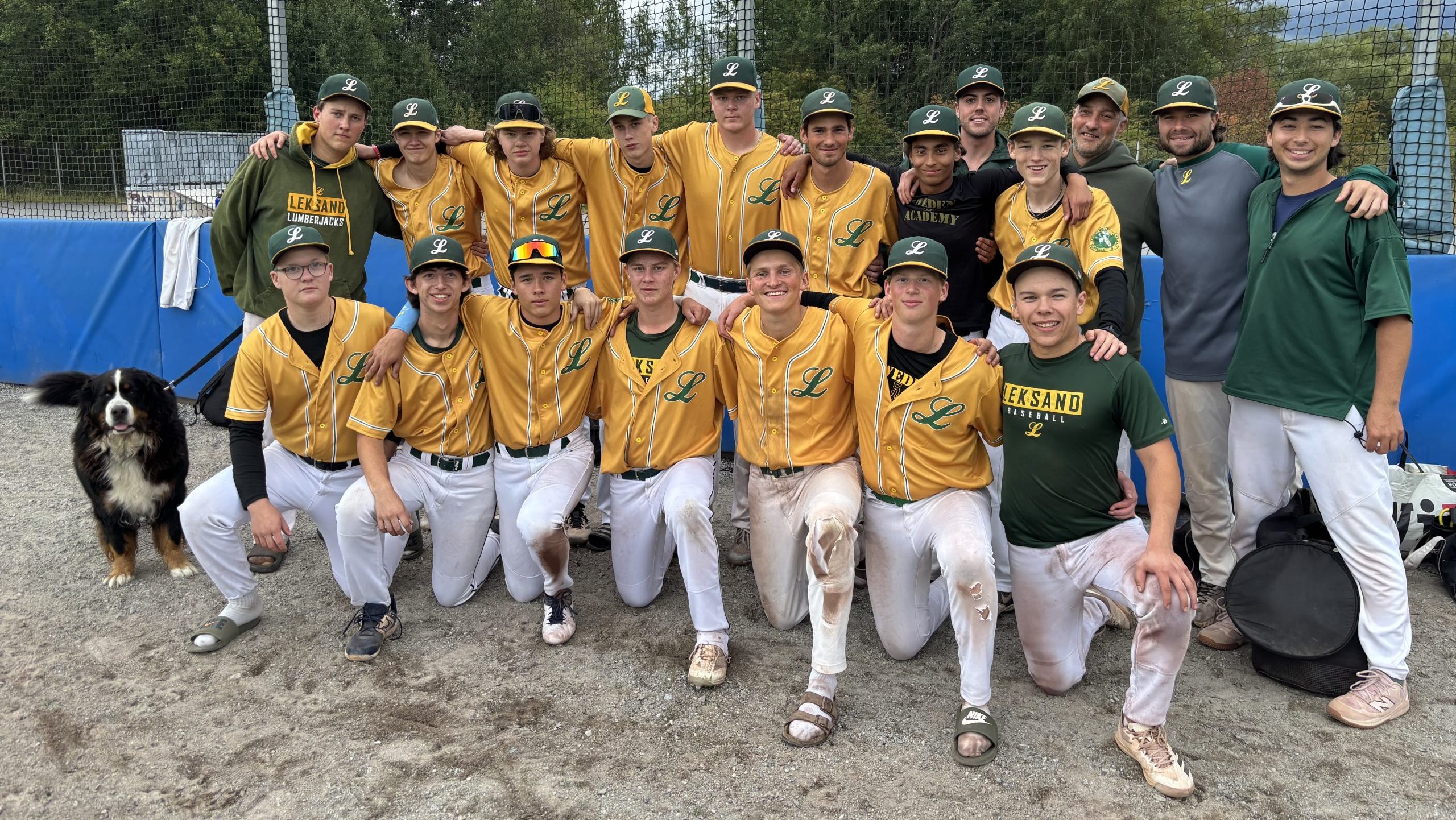 Gruppbild med lagets spelare i gröna och gula tröjor och jackor, samt klassiska vita smutsiga baseboll-byxor.